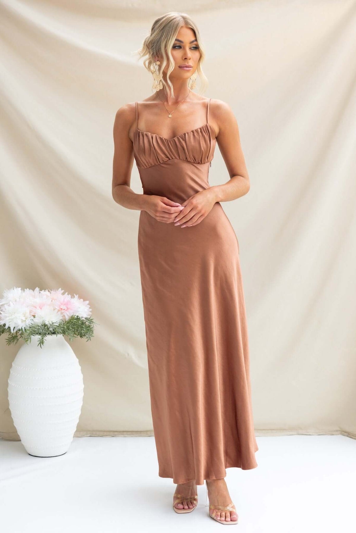 Woman in a Maeya Maxi Dress with gathered bust and adjustable straps, showcasing satin fabric and elegant design.
