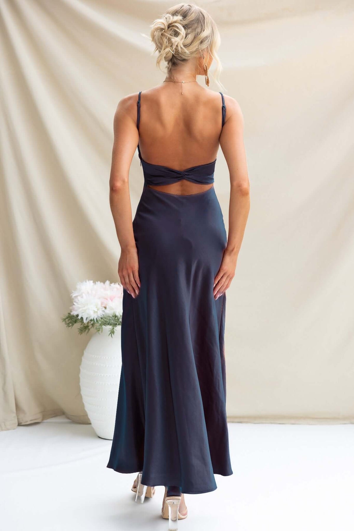 Back view of a woman in a navy satin Maeya Maxi Dress with adjustable straps and cut-out details.