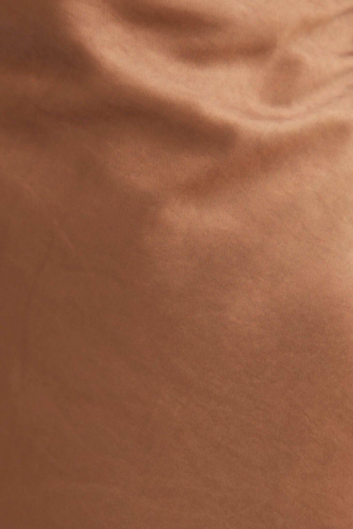 Close-up of smooth satin fabric in warm brown color, showcasing soft texture and rich hue.