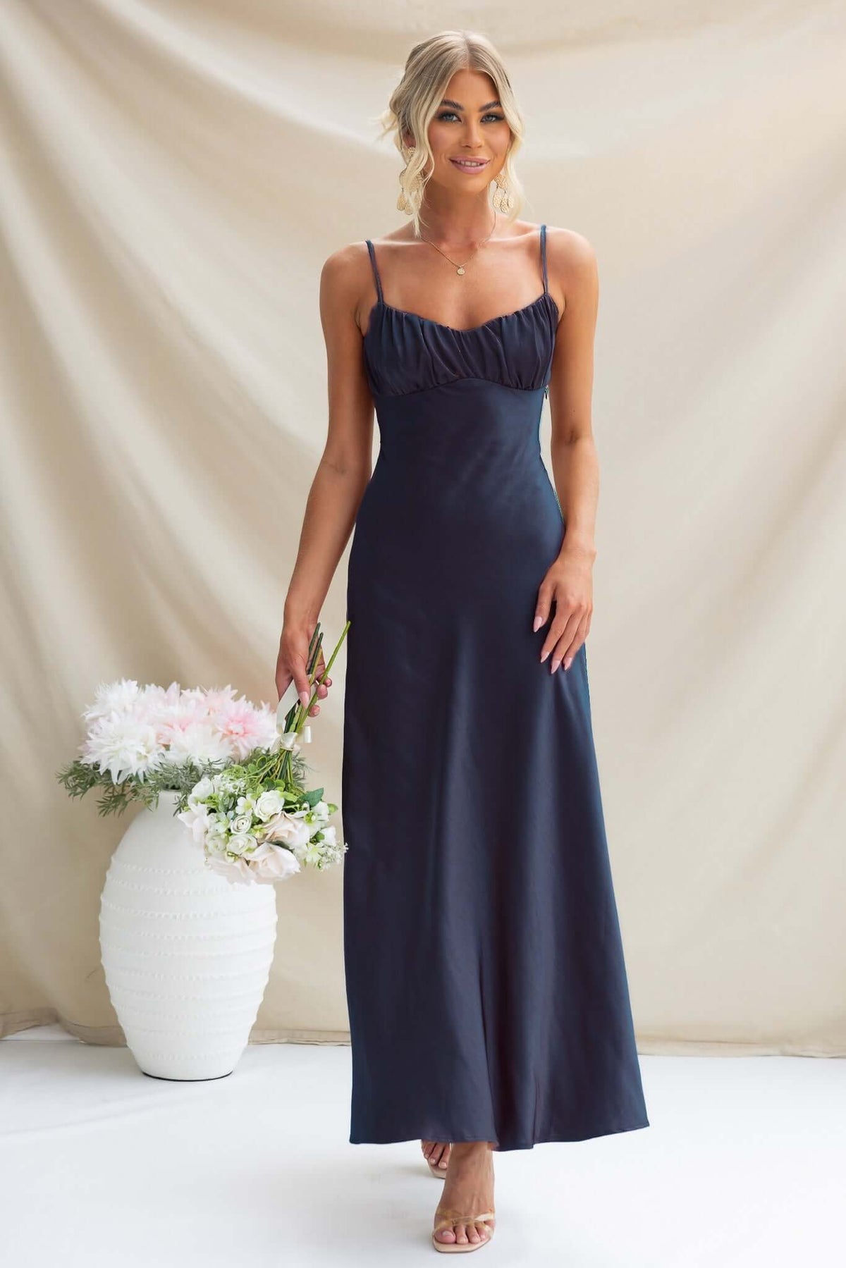Model wearing Maeya Maxi Dress, a navy satin gown with adjustable straps and gathered bust detailing.