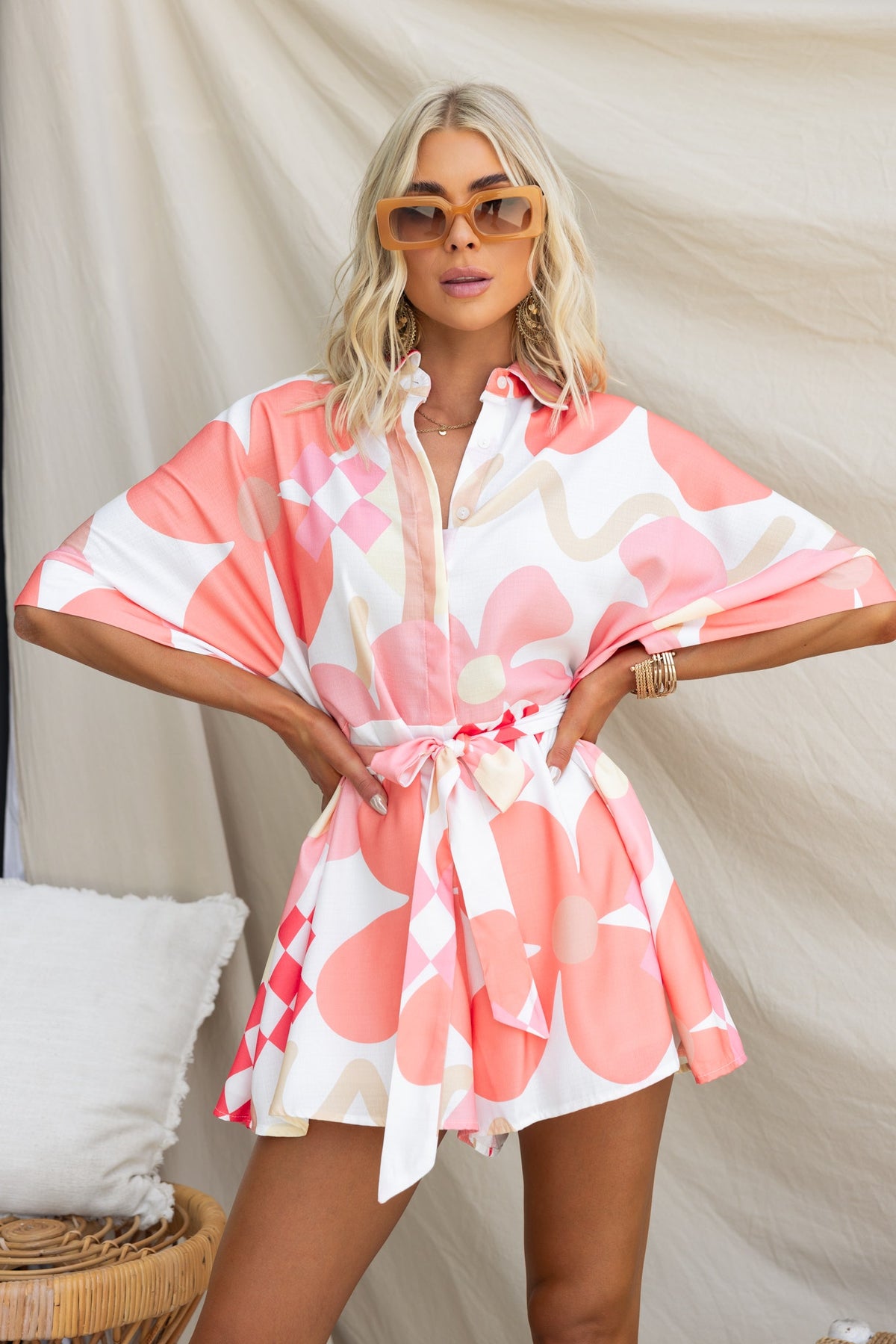 Model wearing a stylish Sundown Playsuit with abstract print, button-up collar, and removable fabric tie.