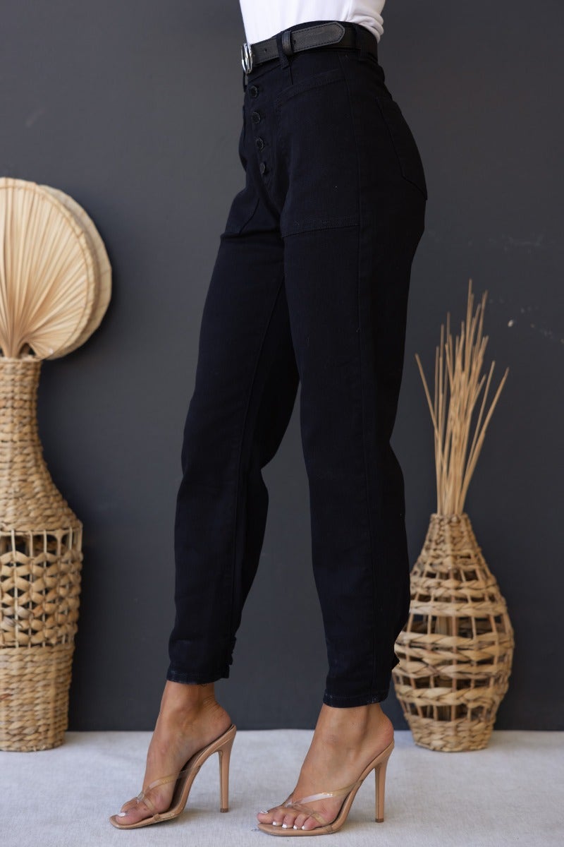 Watson Jeans: Black mid-high waist denim with button-up front, ankle cuffs, and a fitted silhouette, paired with heels.