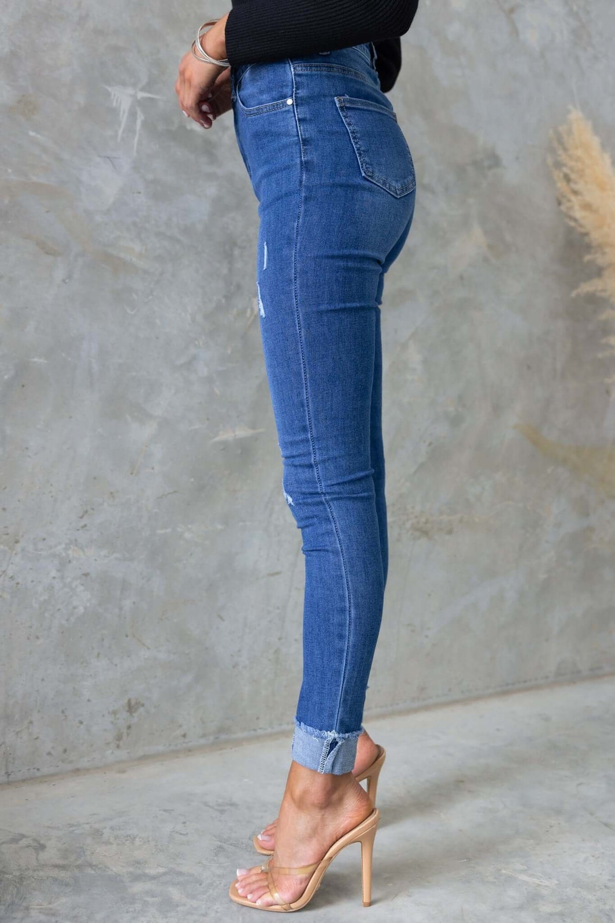 Side view of Lettie Jeans featuring a mid-high waist, distressed details, and stretch denim fabric.