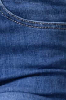 Close-up view of distressed denim fabric from Lettie Jeans, featuring mid-high waist and front pocket detail.