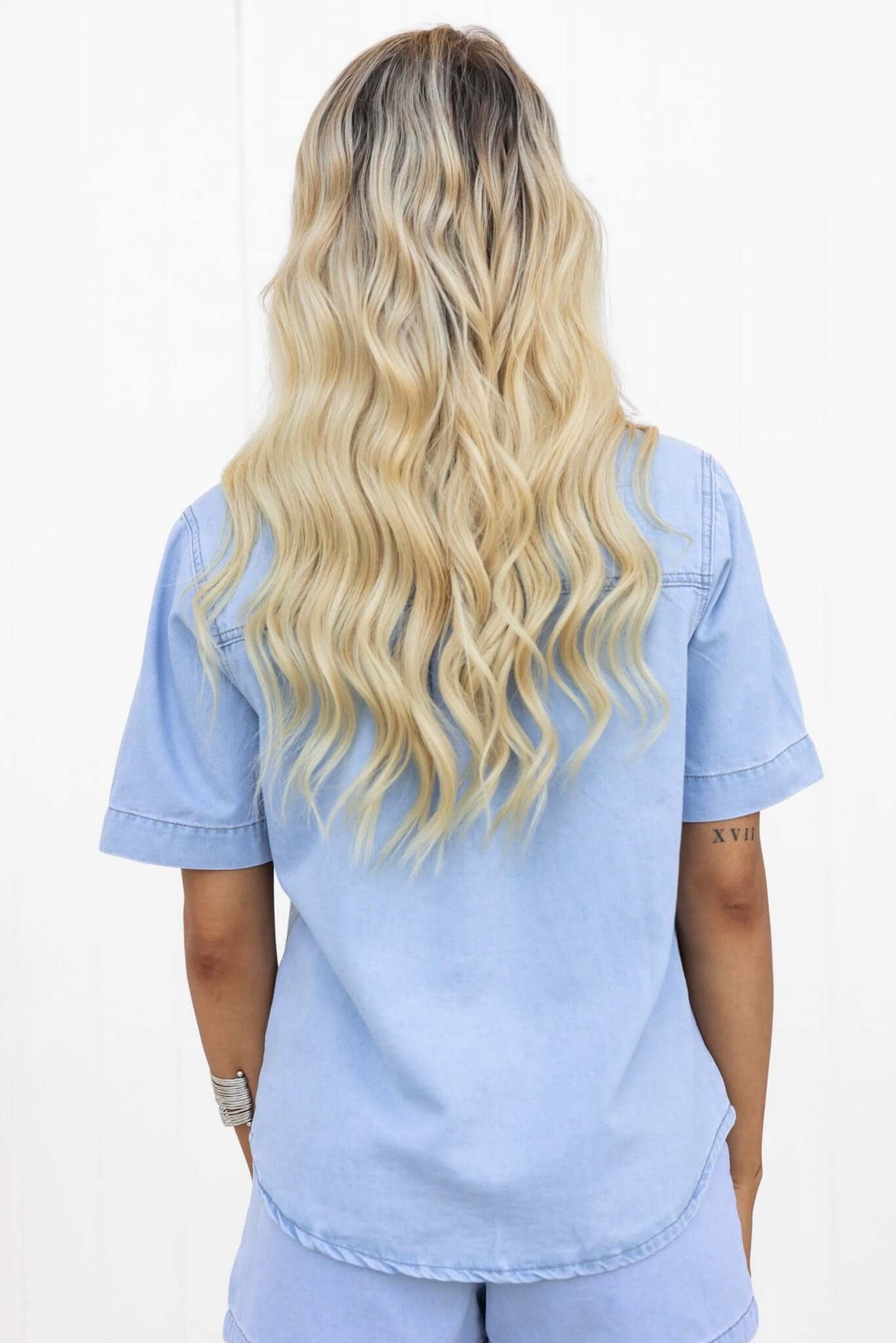 Back view of a woman wearing a chambray Winslow shirt with a button-down front and pocket.