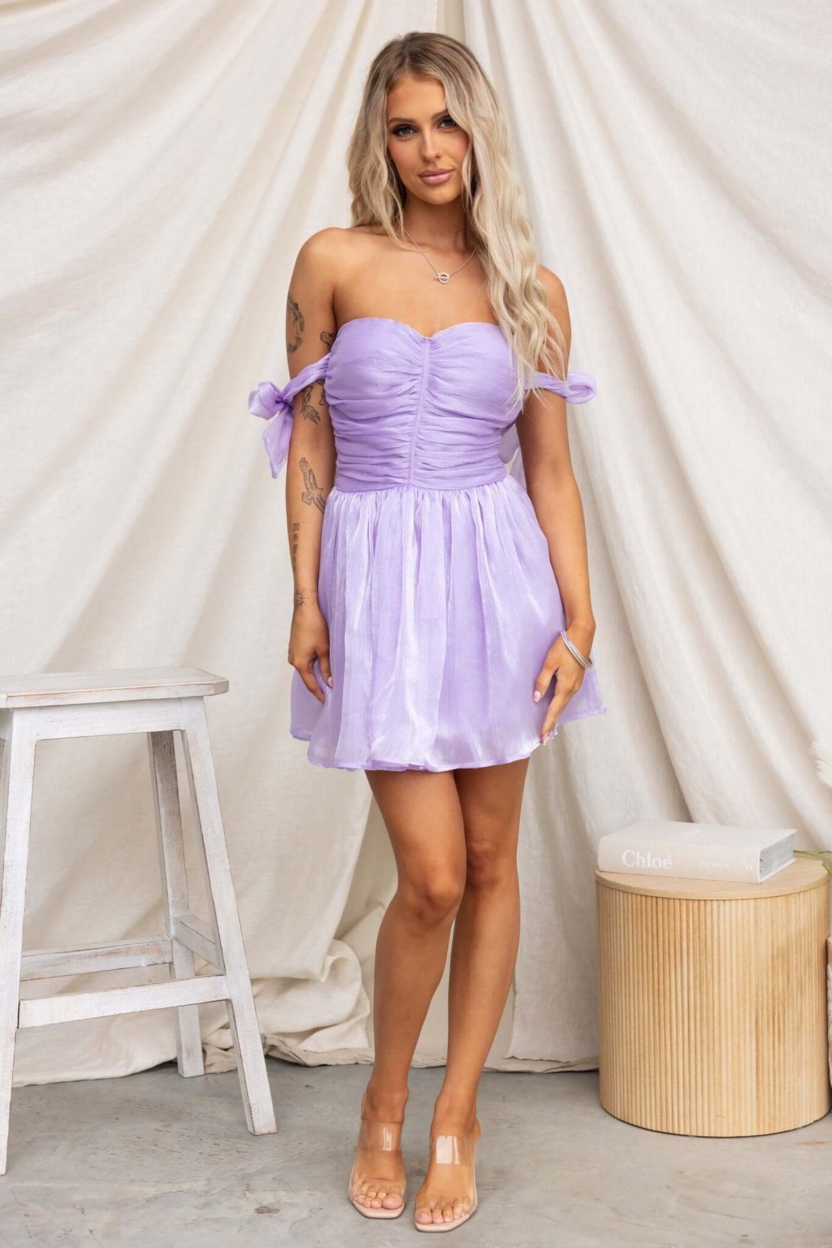 Model wearing a lavender Irena Dress with adjustable tie straps and tulle underskirt against a light backdrop.