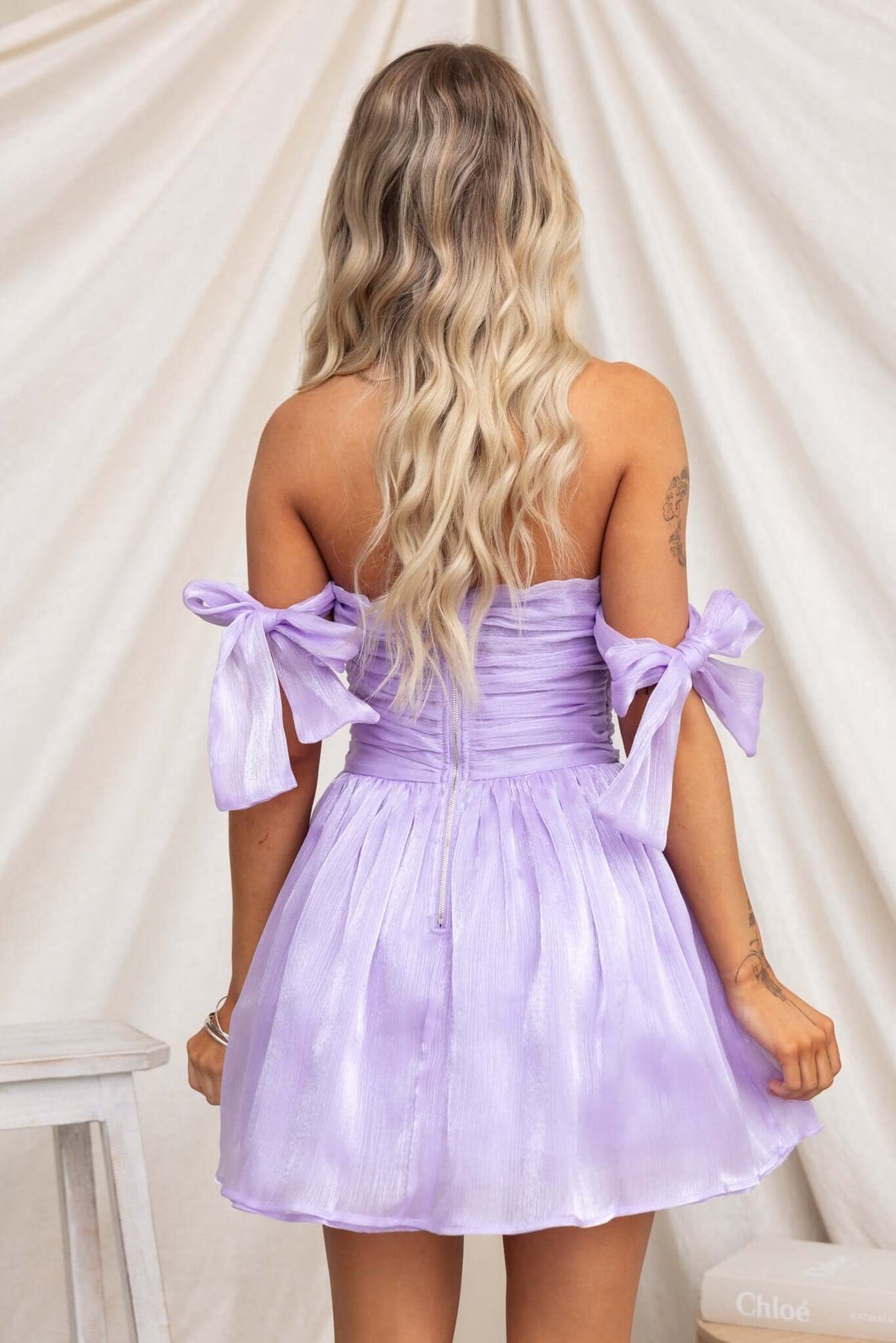 Back view of a lilac Irena Dress with adjustable tie straps and tulle underskirt, showcasing its sheen and elegant design.