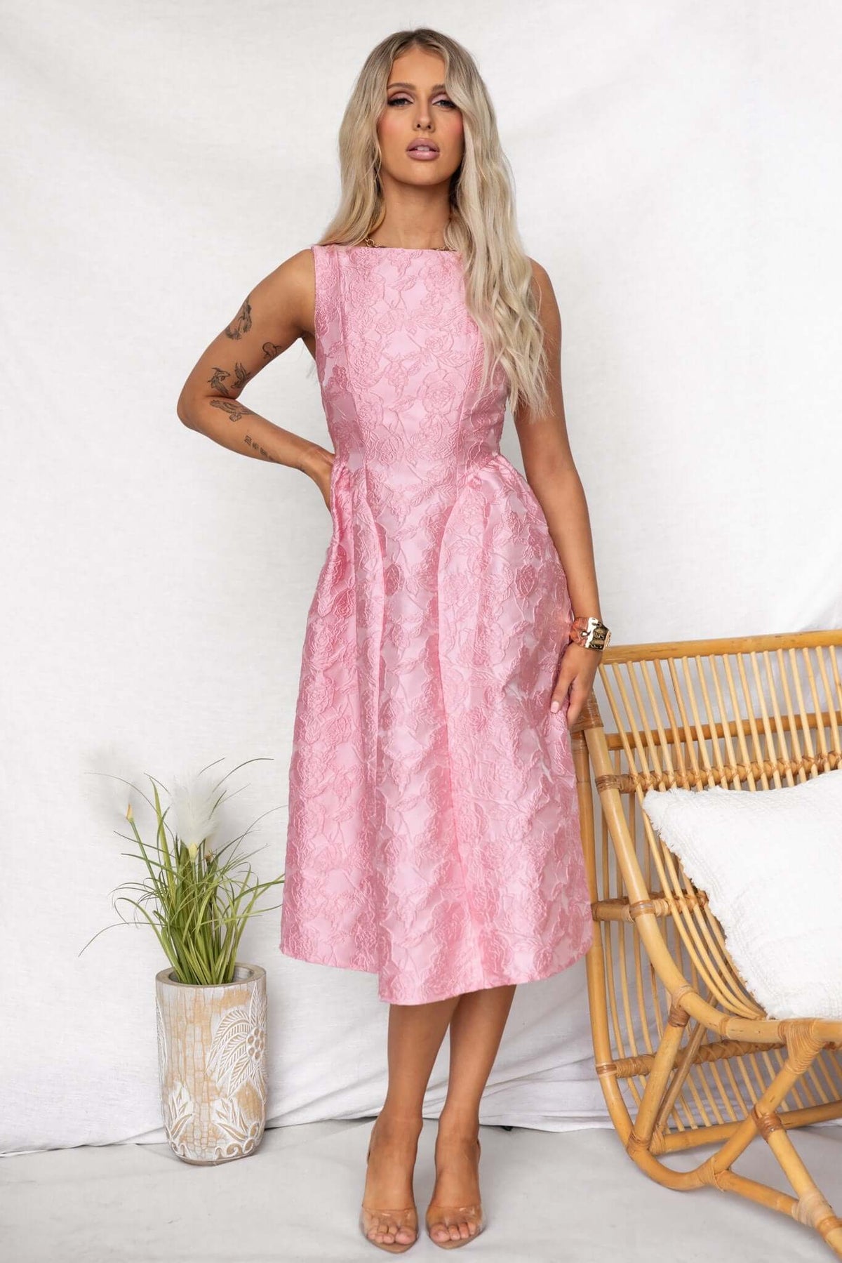 Model wearing a Jadyne Midi Dress in pink, featuring a textured design and structured silhouette, styled with a chic hairstyle.