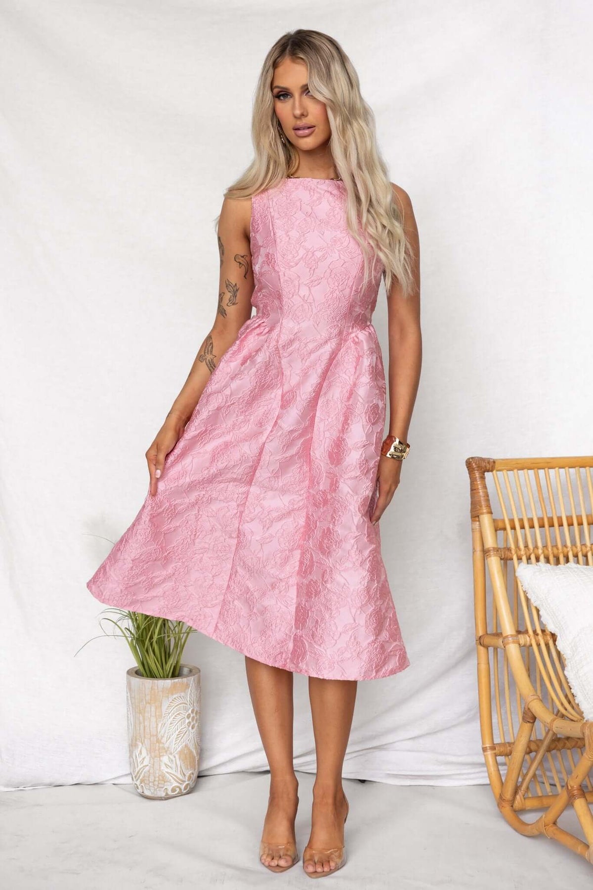 Model wearing a Jadyne Midi Dress in pink, featuring textured material and a flattering silhouette.
