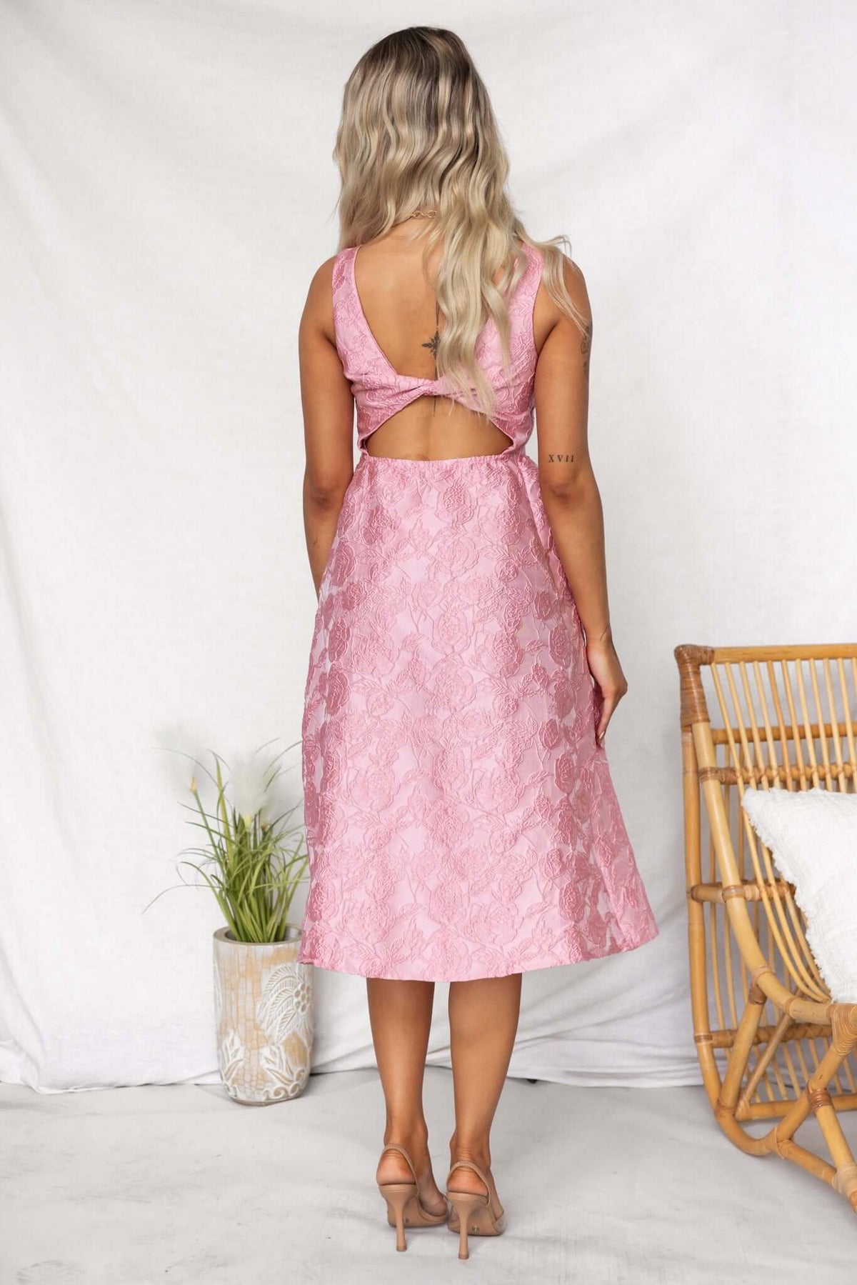 Back view of Jadyne Midi Dress in pink, featuring textured material and a cutout detail.