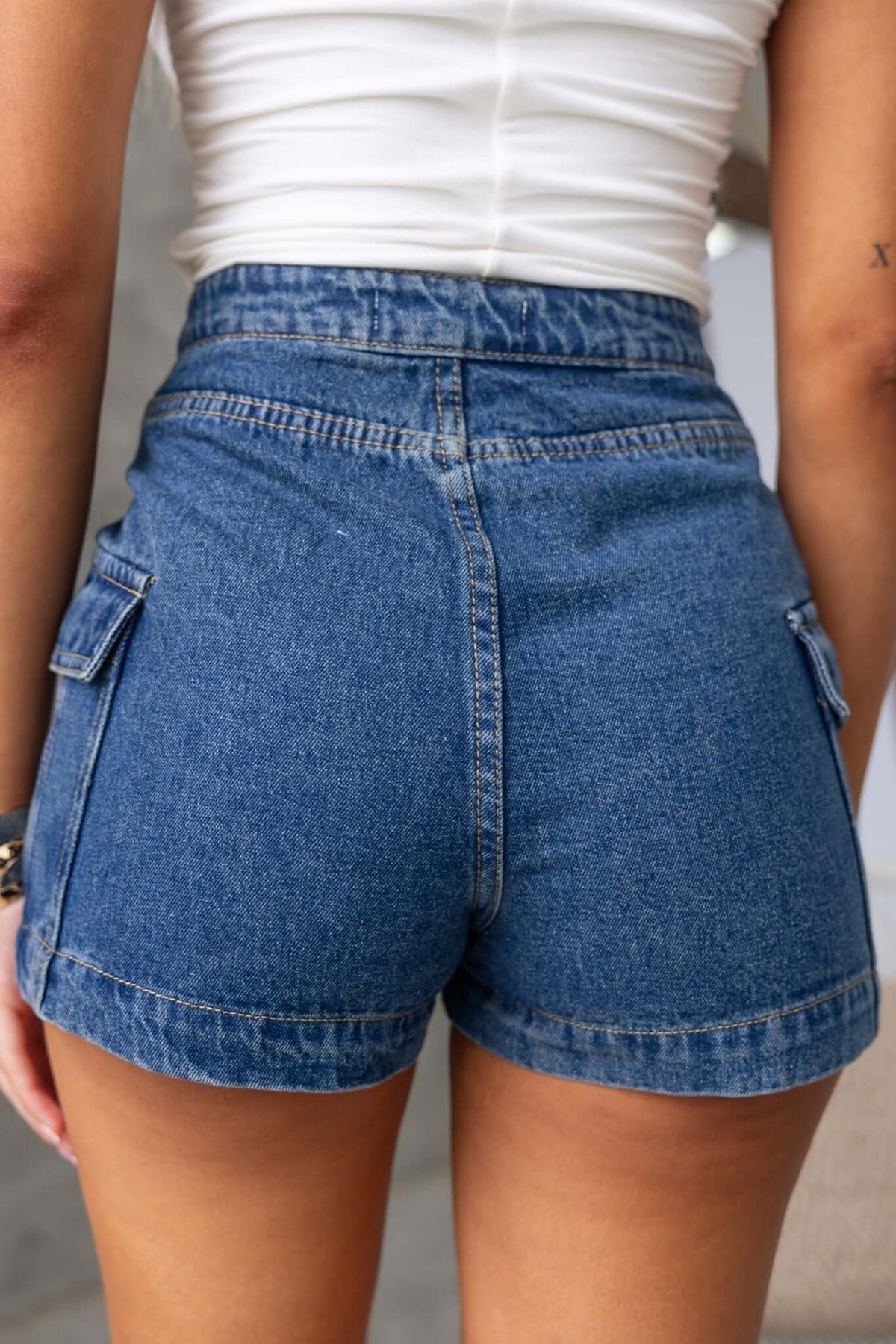 Back view of Osment Denim Shorts showing mid-high waist fit and side pockets, styled with a fitted top.