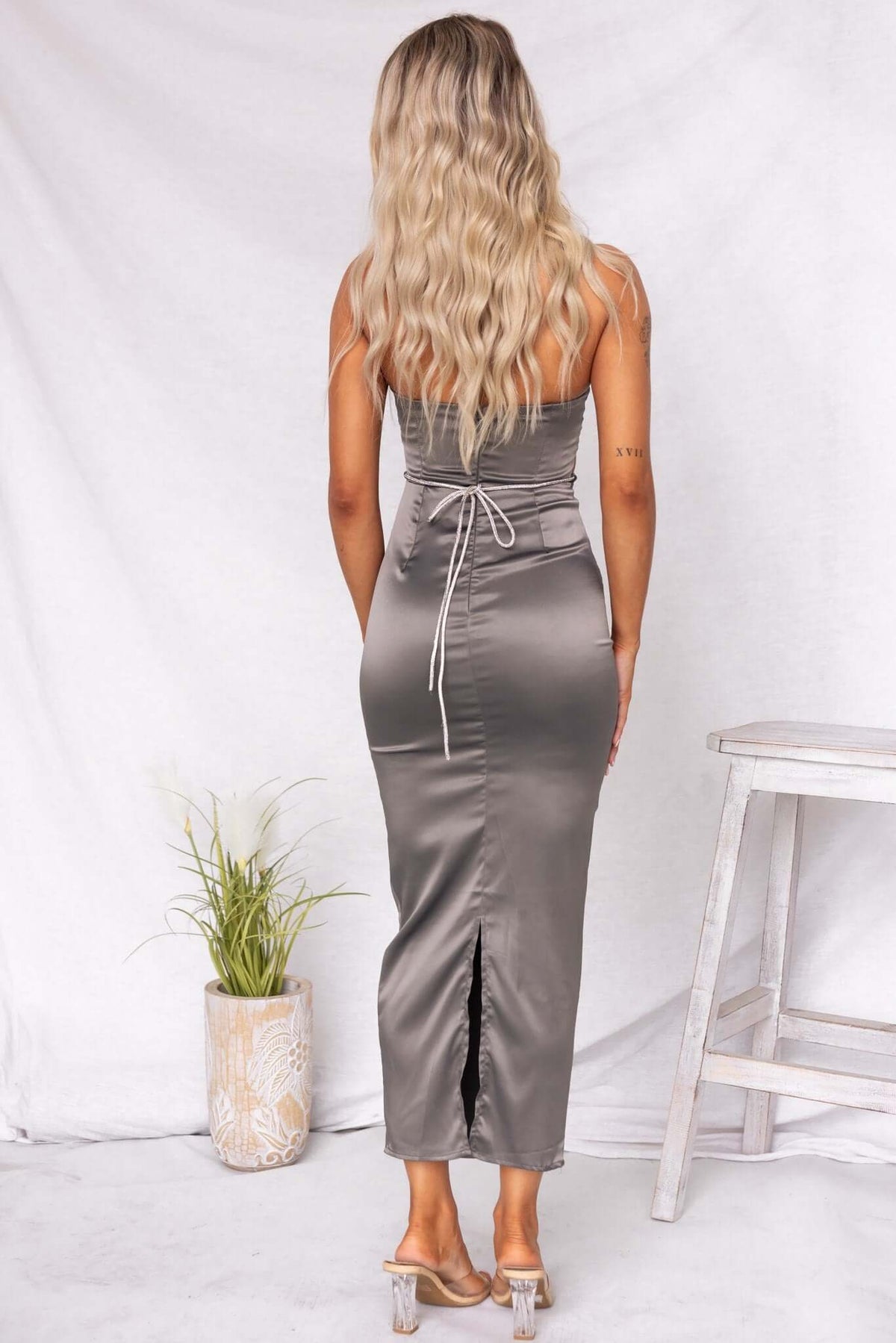 Model showcasing the back of a satin strapless Louise Maxi Dress with adjustable tie and back split.