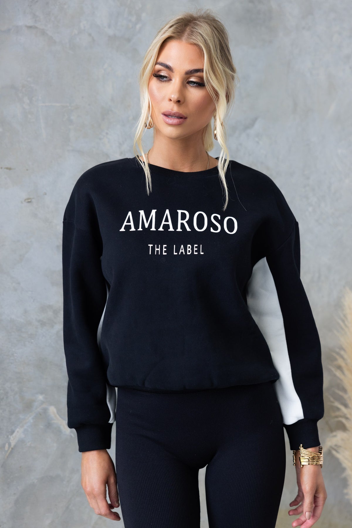 Model wearing black Amaroso the label jumper with white accents, round neckline, and ribbed cuffs.