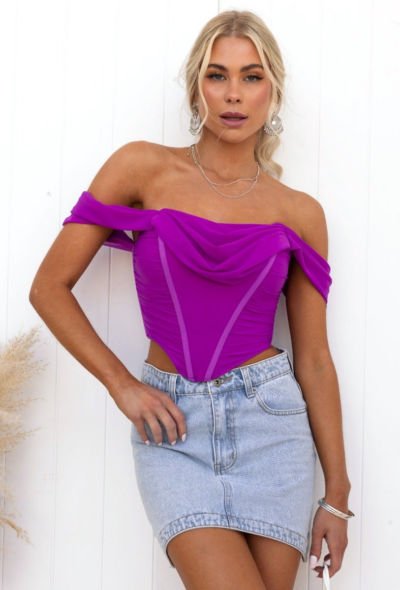 Taria Top in vibrant purple, off-shoulder corset design with boning and zipper detail, styled with a denim skirt.