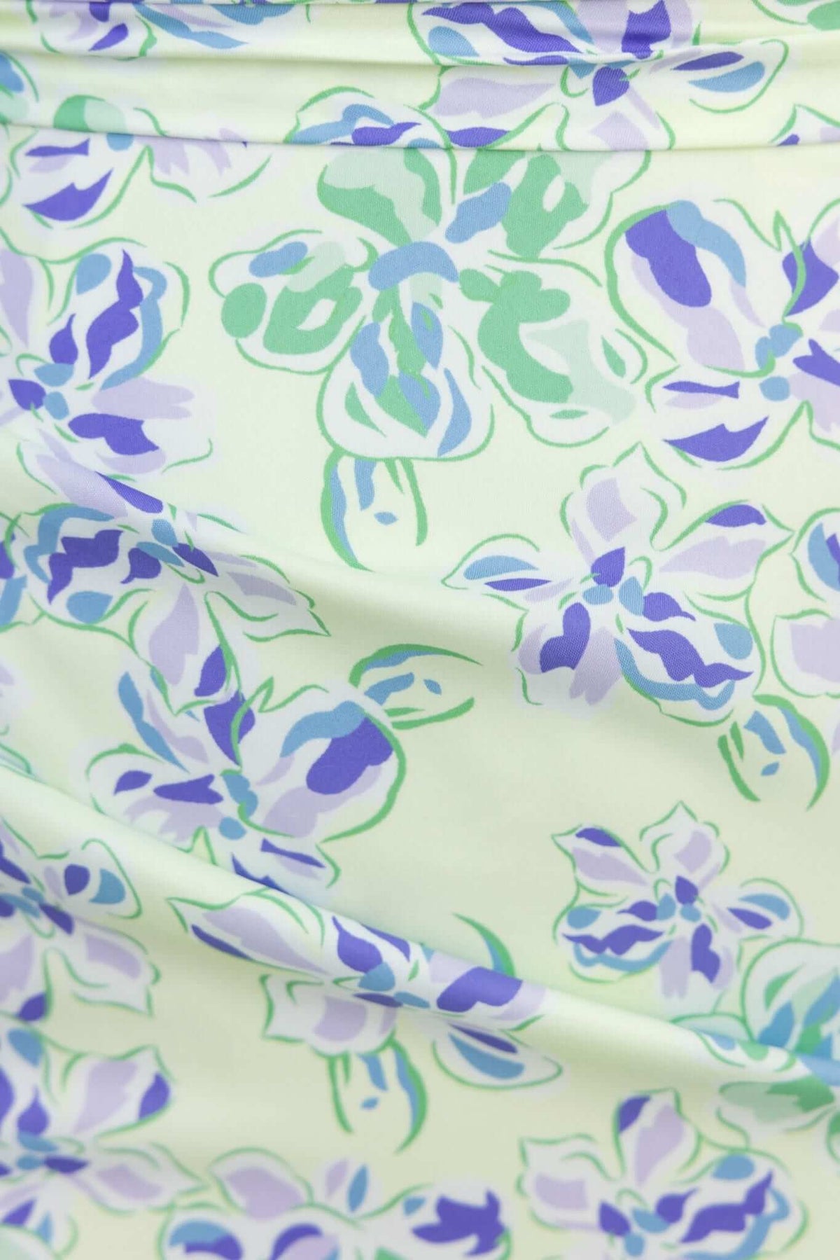 Close-up of a floral print in soft pastel colors featuring light green, purple, and blue accents on a dress.