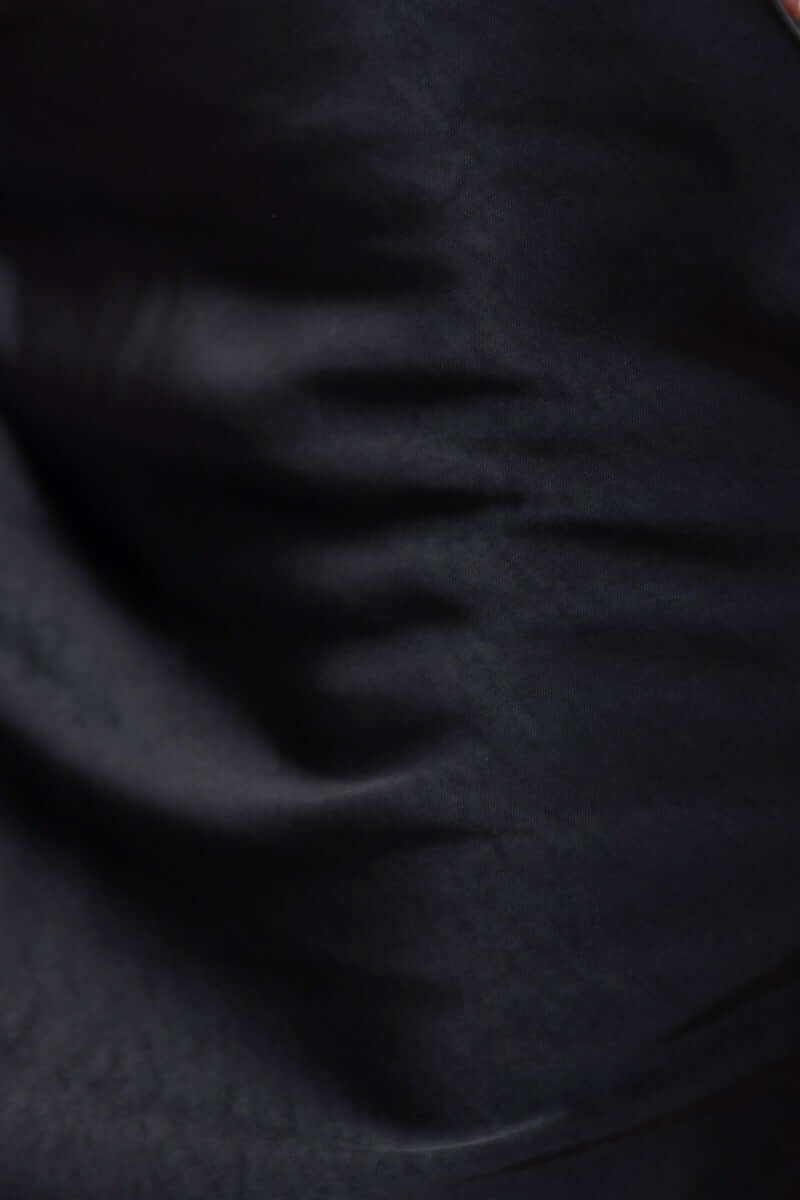 Close-up of black satin fabric showing smooth texture of the Under Control Top, adjustable straps and sleek design.