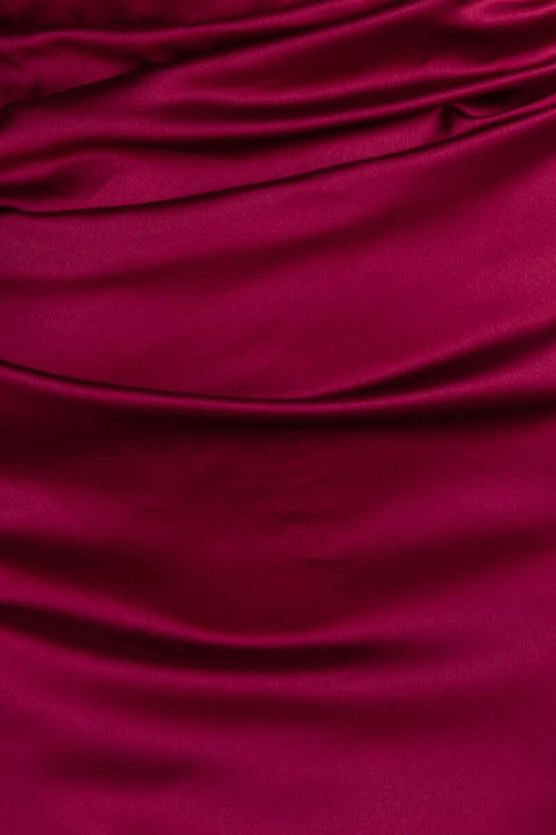 Close-up of luxurious satin fabric in deep burgundy, showcasing elegant draping for the Dimmi Maxi Dress.