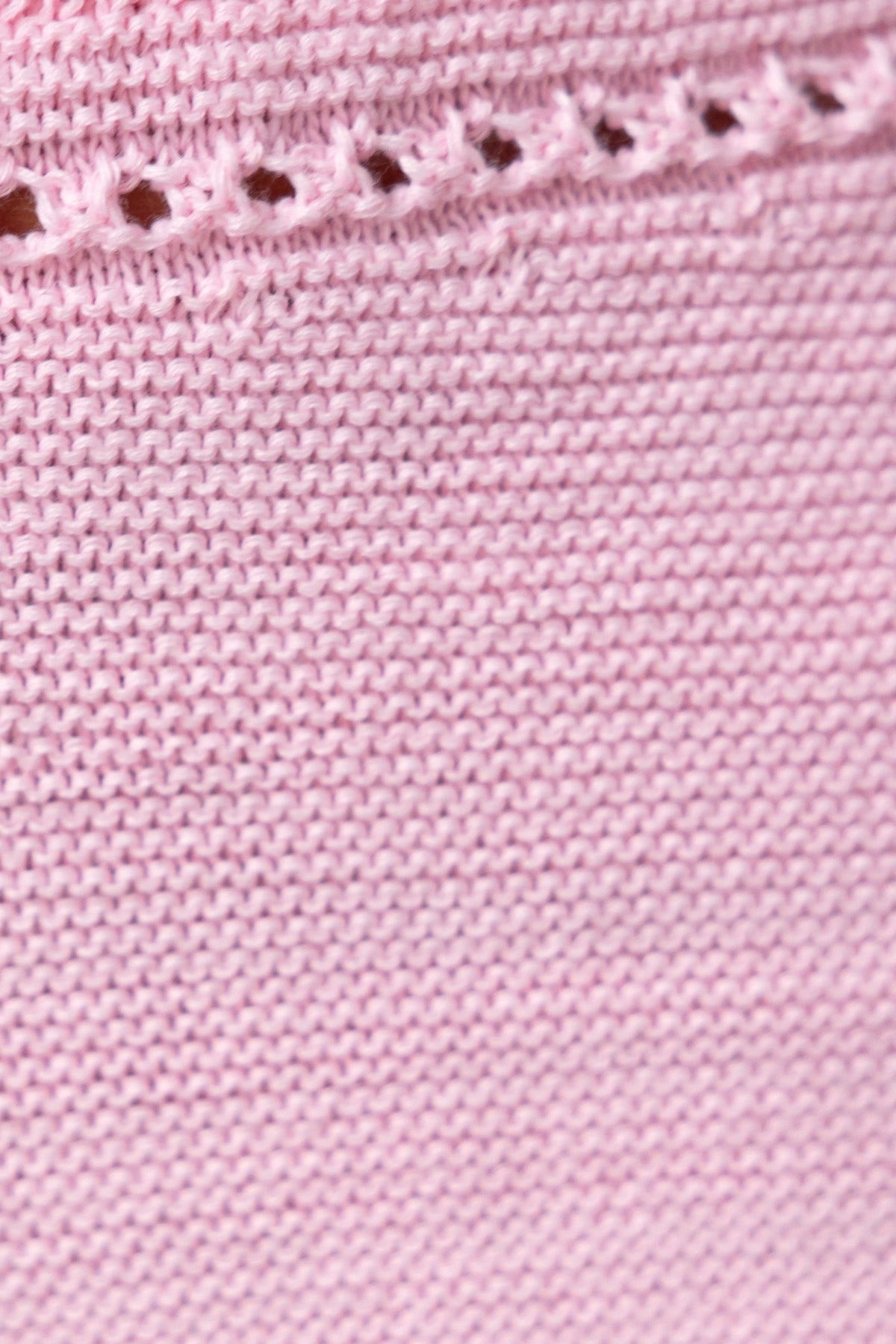 Close-up of a pink knit fabric with strapless ring detail, showcasing a semi open weave texture.