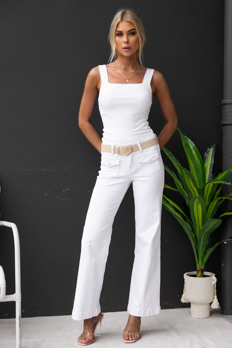 Model wearing white Gretchen Jeans with a square neck top, showcasing a stylish summer look against a neutral backdrop.