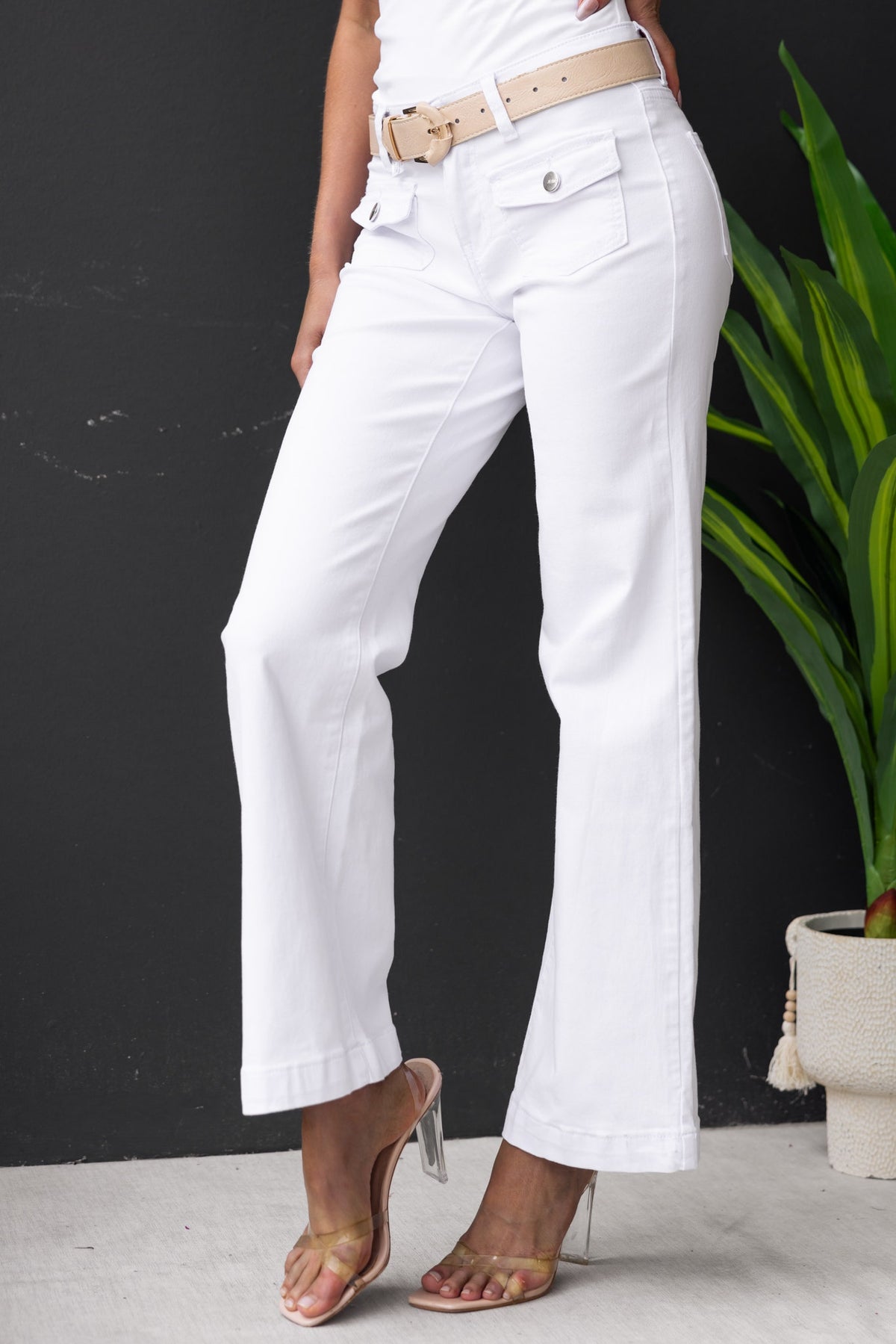Model wearing white denim Gretchen jeans with pockets and a belt, featuring a straight leg fit and stylish design.