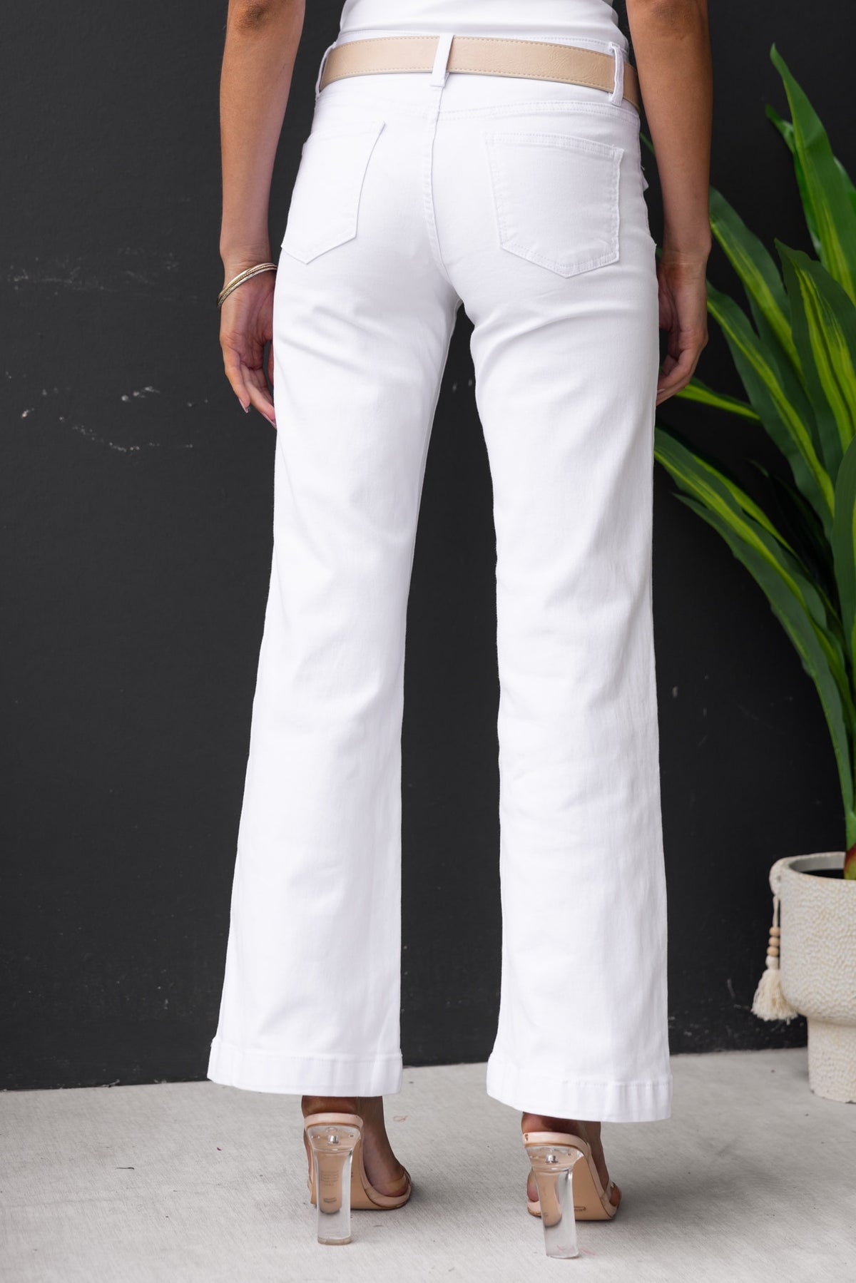Back view of a woman wearing white denim jeans with a mid-low waist fit and straight leg design.