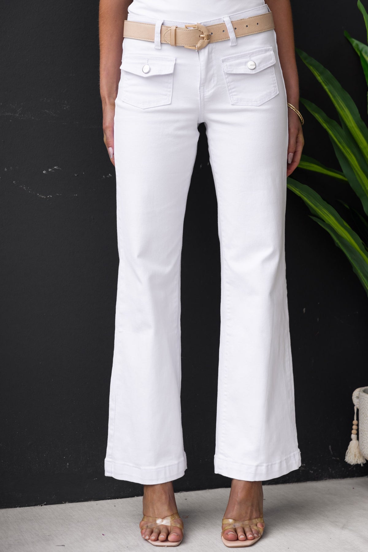 White denim jeans with straight leg fit, mid-low waist, and front/back pockets. Styled with a belt and open-toe sandals.