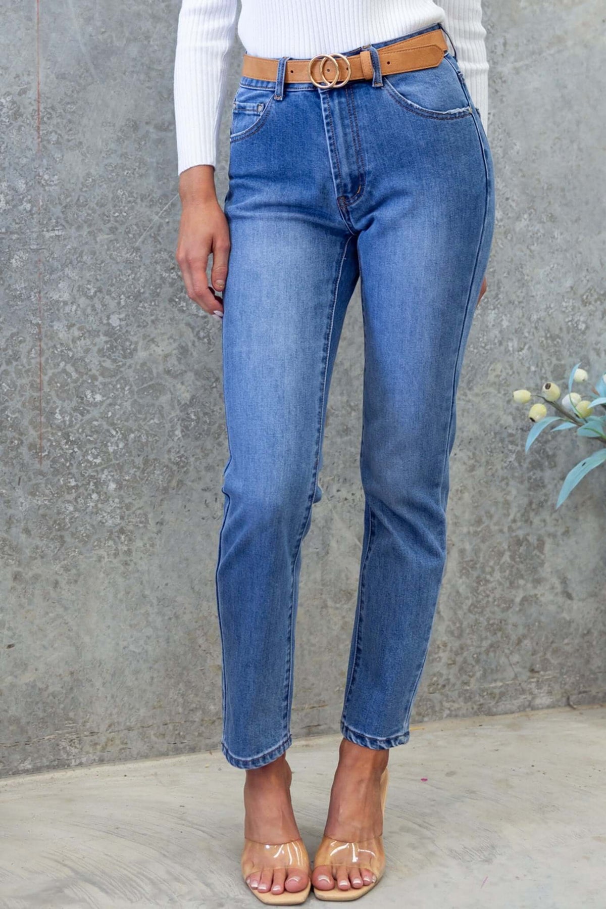 Selma Jeans: mid-high waist denim jeans with a straight leg fit, styled with a belt and worn casually.