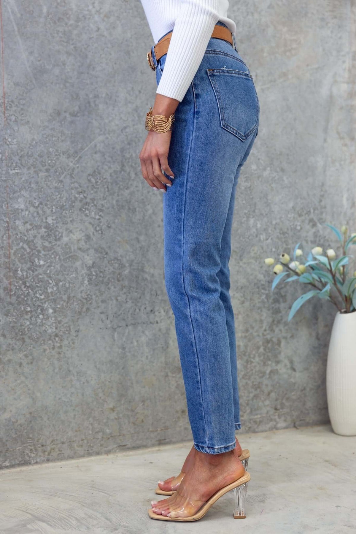 Side view of Selma Jeans featuring a mid-high waist, straight leg fit, and light blue denim, styled with a white top.