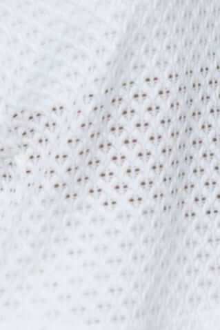 Close-up of textured white fabric showing a detailed knit pattern, highlighting its breathable quality.