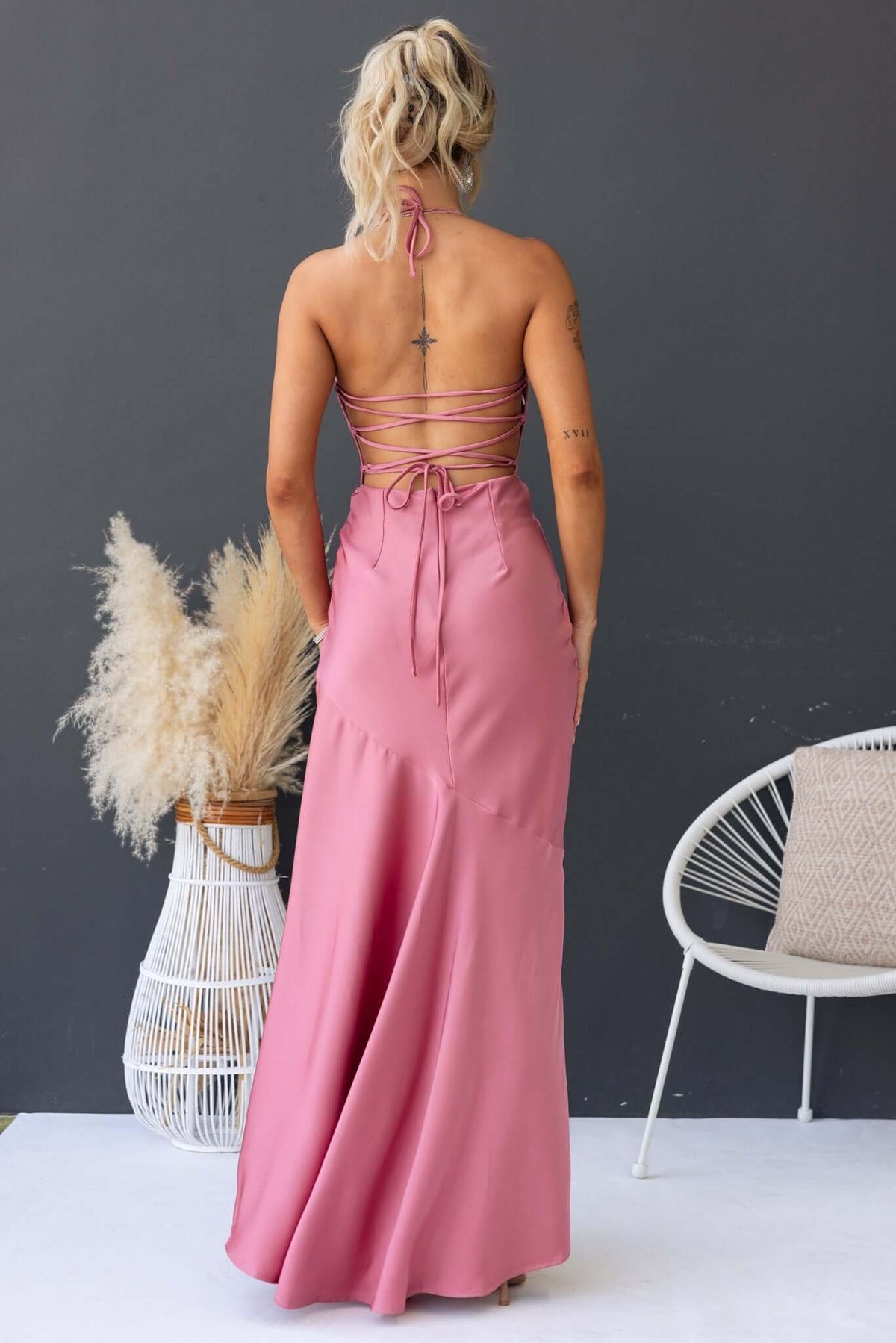 Back view of a woman in a pink Ramona Maxi Dress with tie straps, showcasing a flowing silhouette and elegant design.