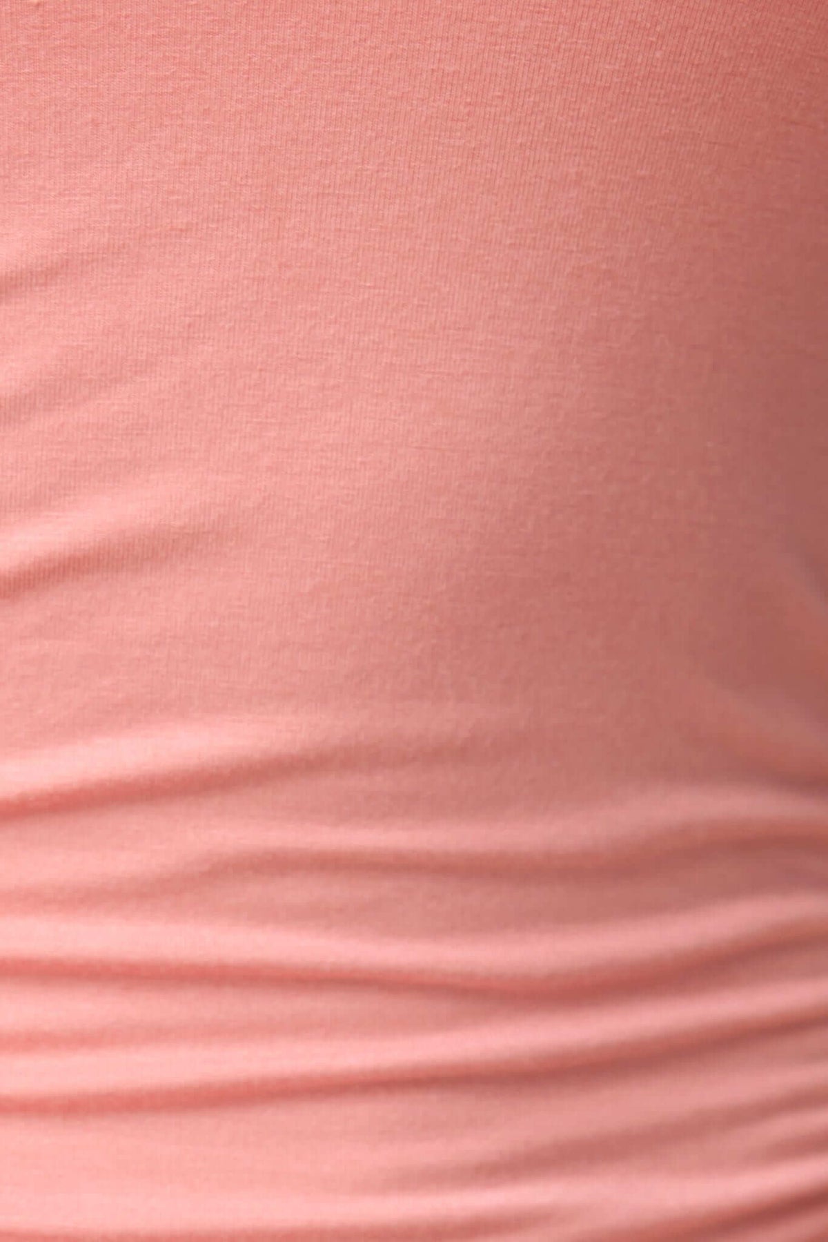 Close-up of the soft fabric of the Lois Midi Dress, showcasing bodycon fit and side ruching detail in a peach color.