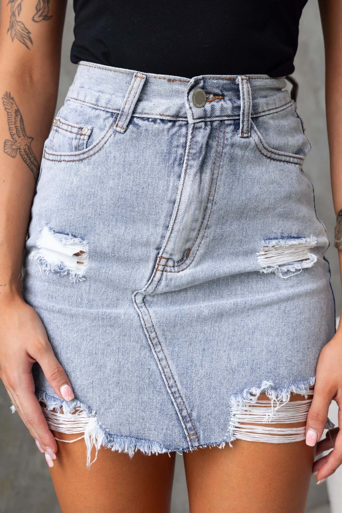 Chico Denim Skirt featuring mid waist fit, distressed details, raw hemline, and front pockets.