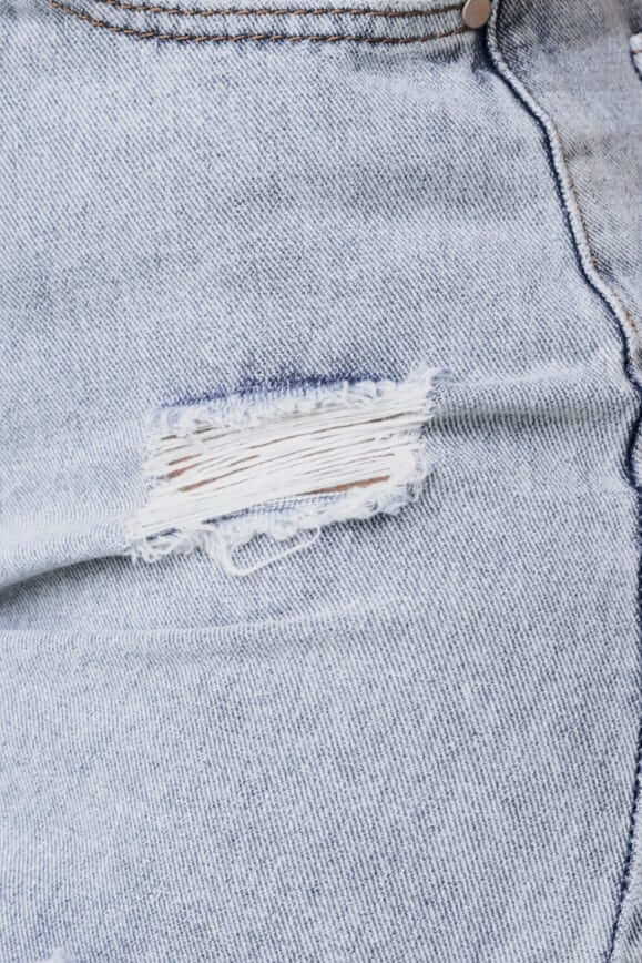 Close-up of distressed detail on Chico Denim Skirt with raw hem and faded blue denim.