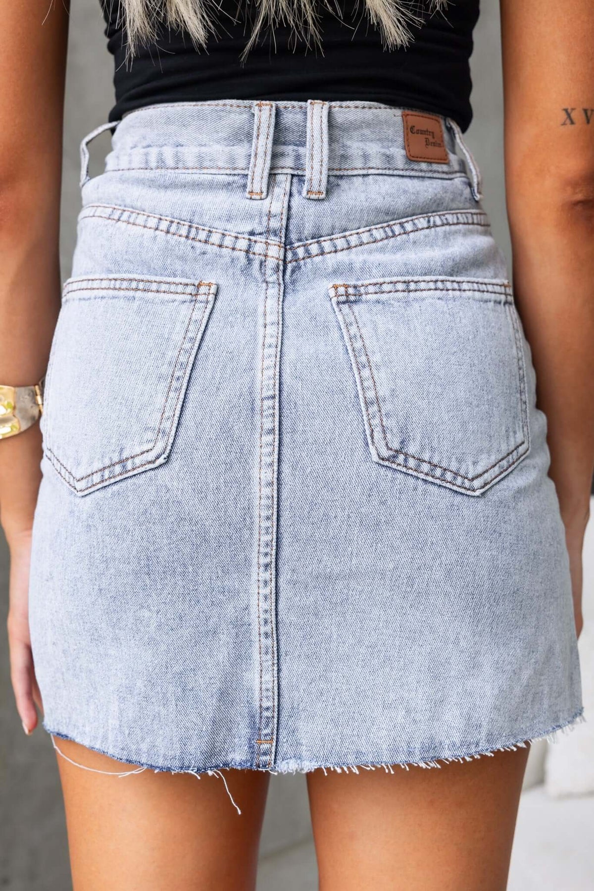 Back view of Chico Denim Skirt featuring a mid waist fit, distressed details, and raw hemline.