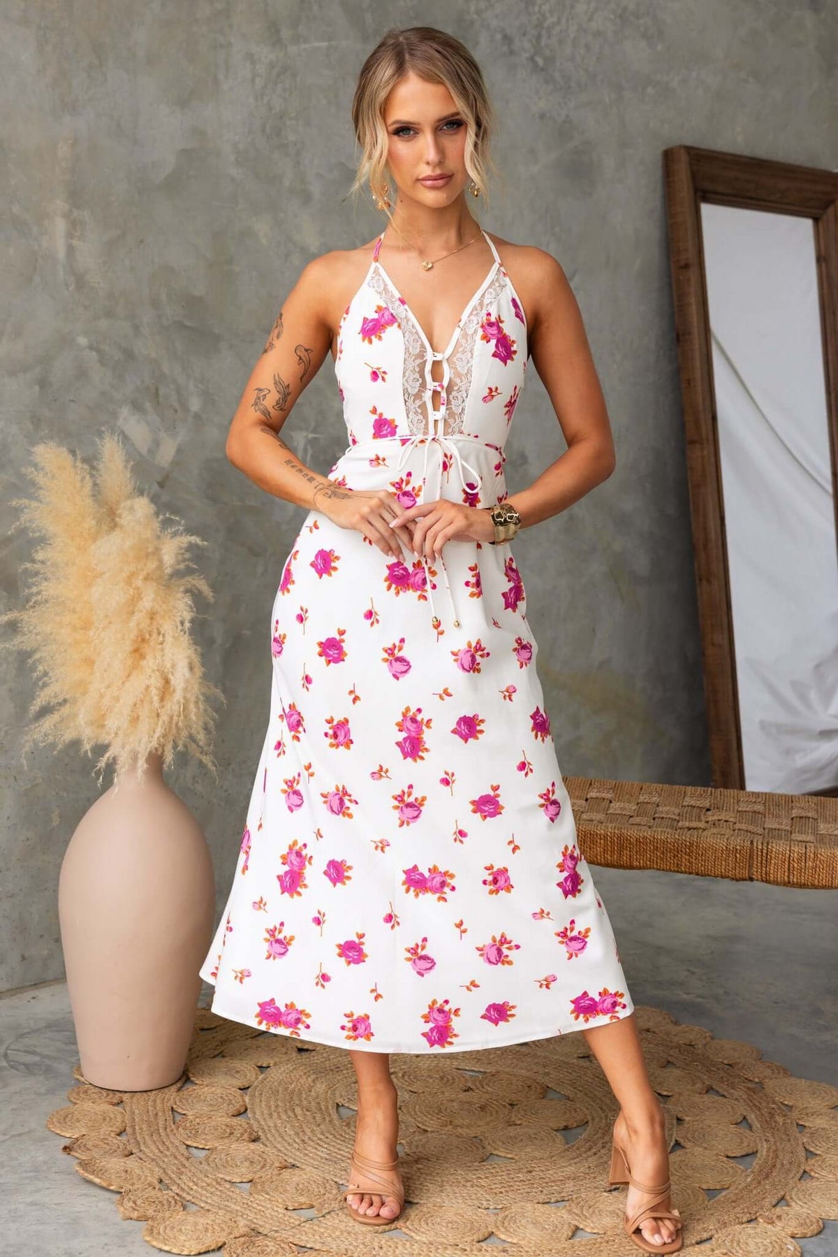 Floral print Paige midi dress with adjustable tie halter neckline and buttons at bust, styled in a natural setting.