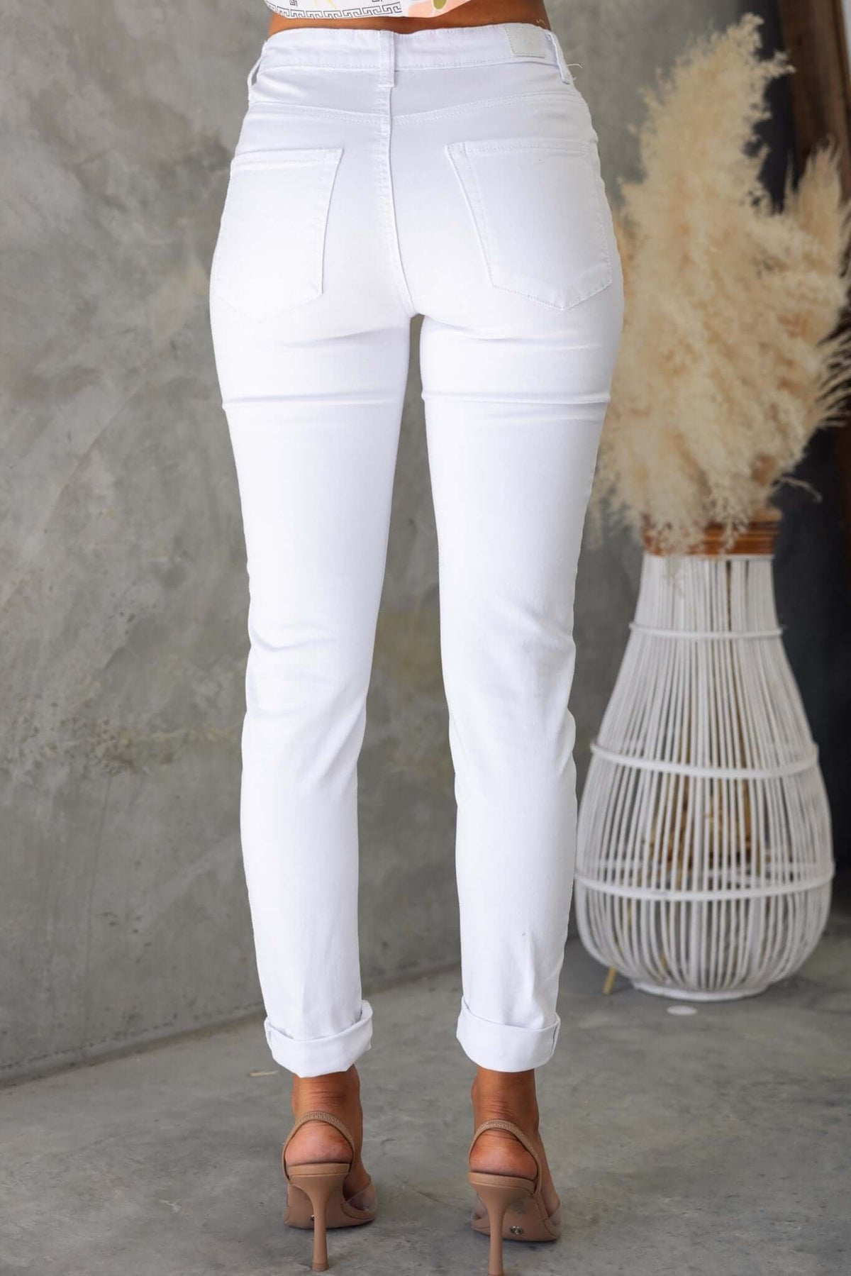 Back view of Narni Jeans in white, featuring a mid-high waist, pockets, and a fitted cut, styled with heeled sandals.