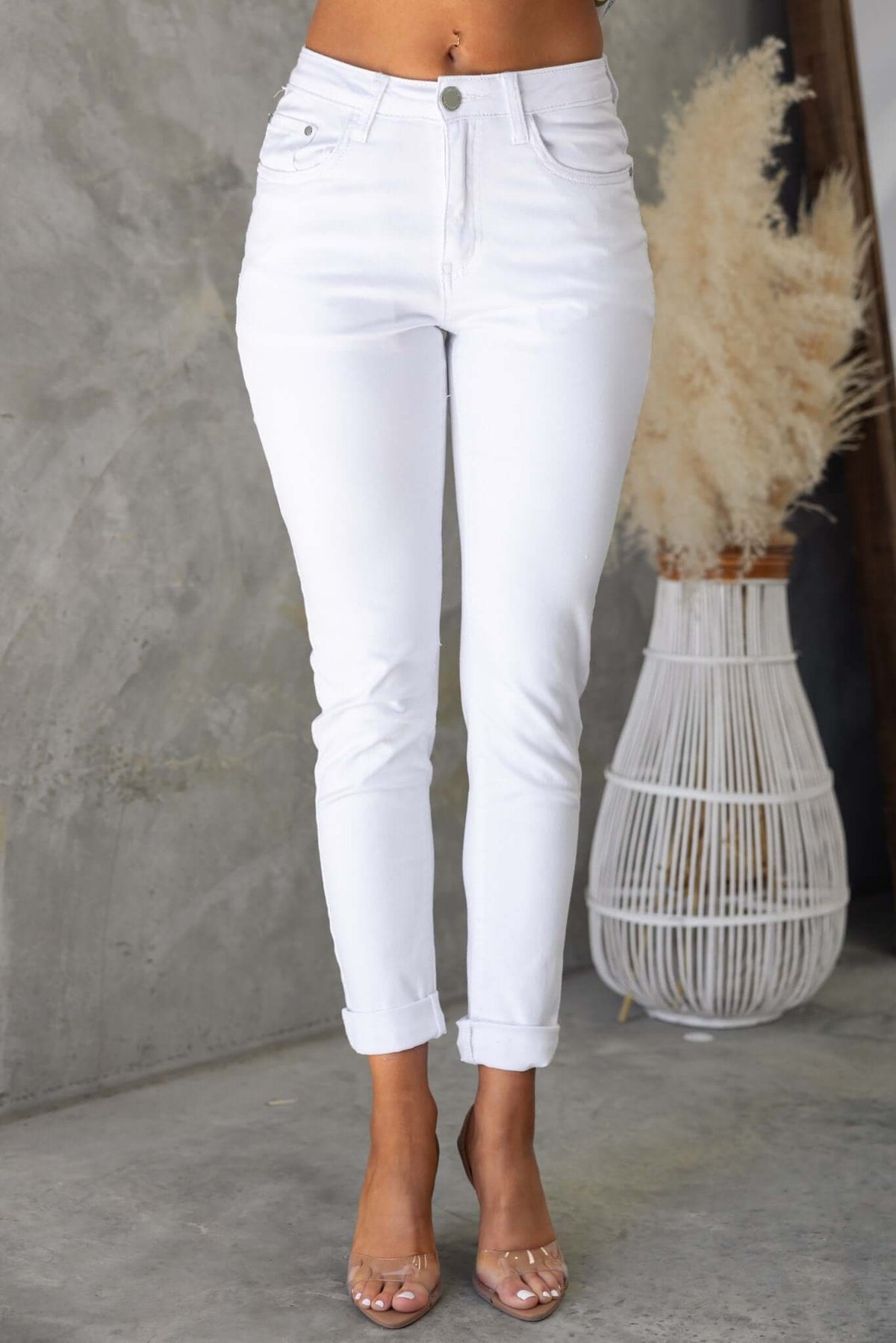White denim Narni Jeans featuring a mid-high waist fit and rolled hems, styled with clear heels.