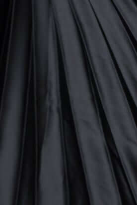 Close-up of accordion pleat black fabric, showcasing texture and flow for the Olympia Maxi Dress.
