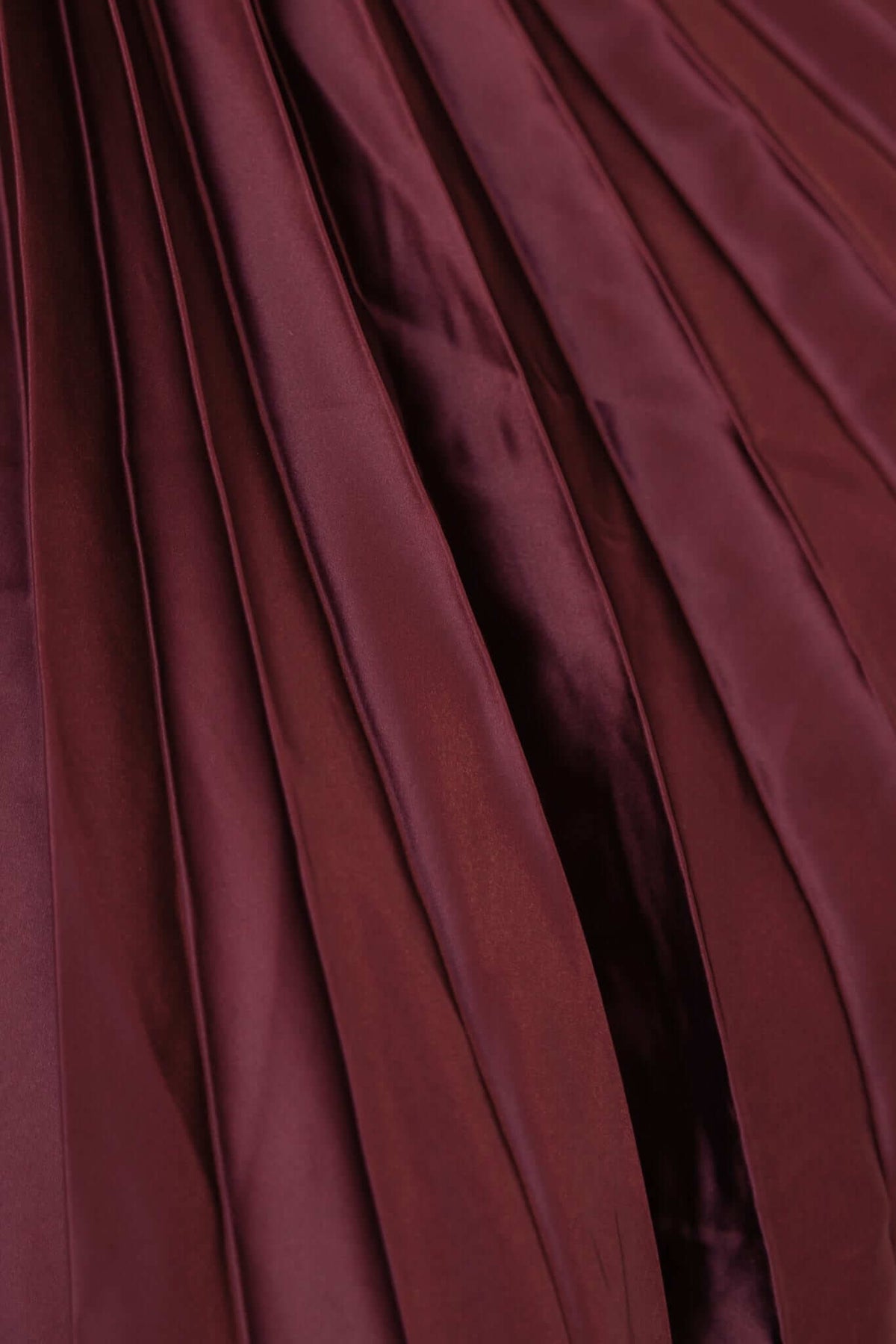 Close-up of accordion pleat material in rich burgundy color, showcasing elegant texture and movement.