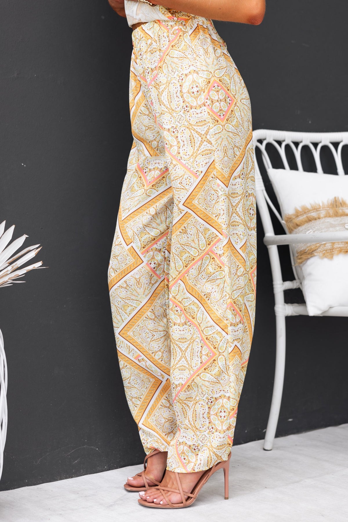 Vivid pants featuring an abstract print and elastic waistband, styled with heels against a minimalist background.