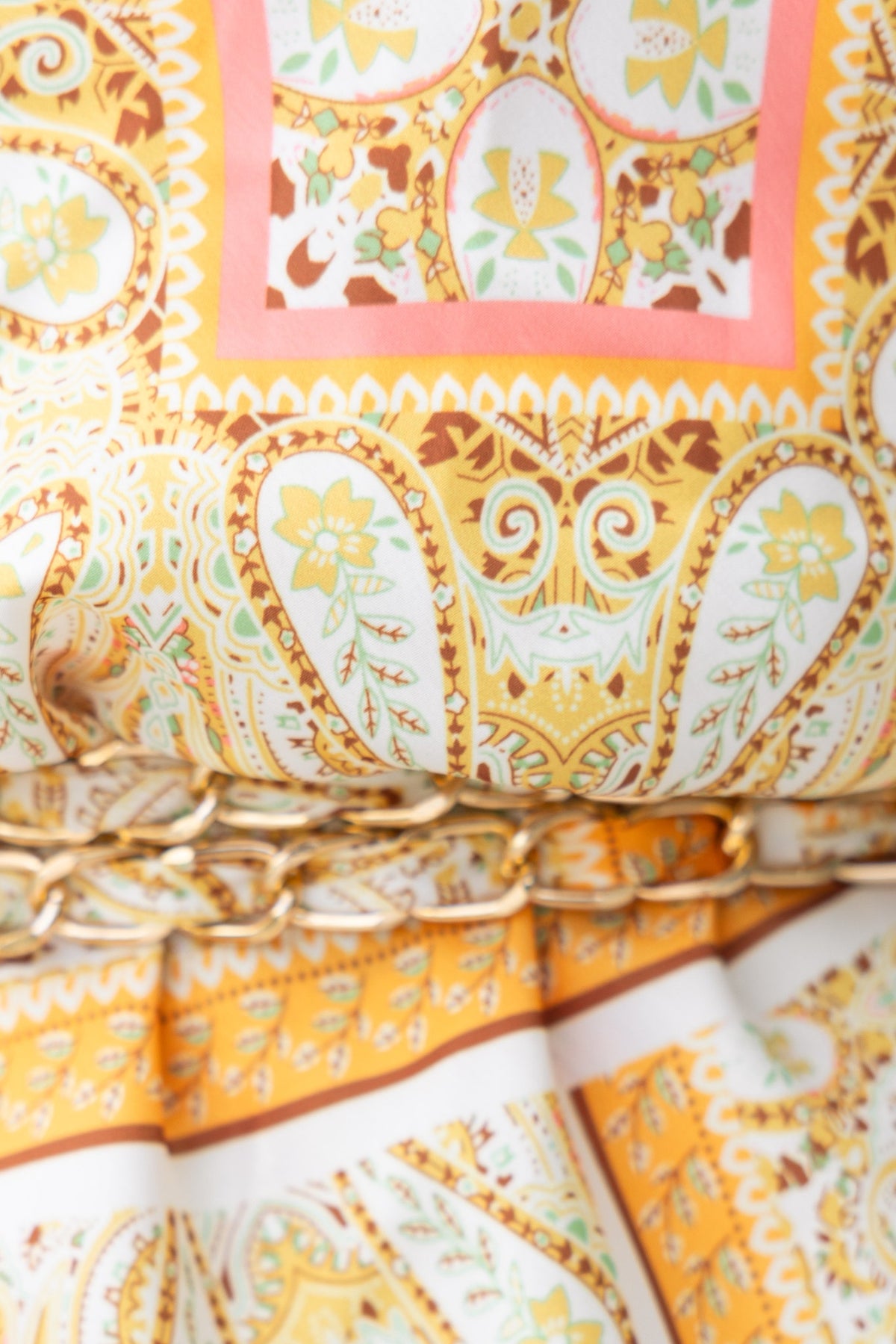 Close-up of vivid abstract print fabric with floral and geometric patterns in yellow, pink, and green tones.