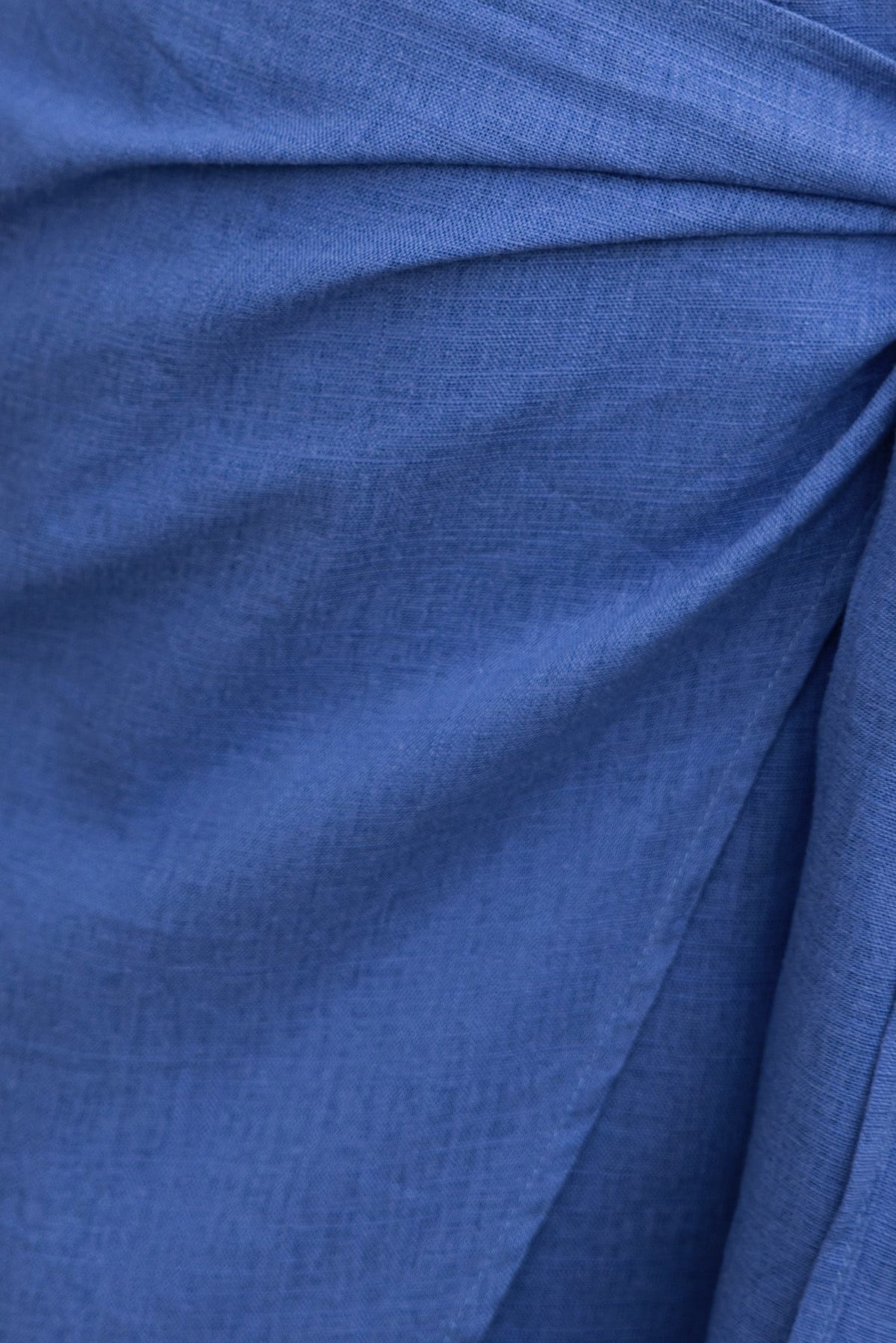 Close-up of the stylish blue fabric of the Kaiden Dress, showcasing linen texture and elegant draping.