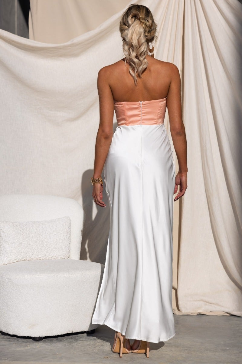 Back view of Katya Satin Maxi Dress in white and peach, showcasing strapless design and elegant split detail.