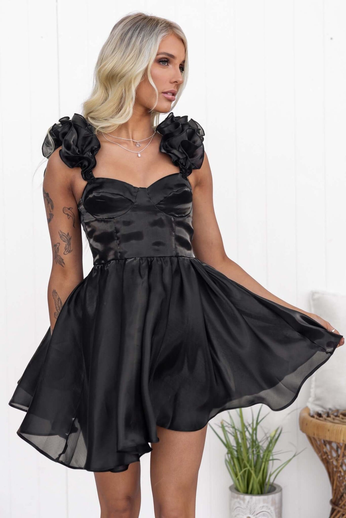 Ermia Dress in black with ruffle straps, featuring a shiny chiffon finish and a flared skirt, perfect for stylish occasions.
