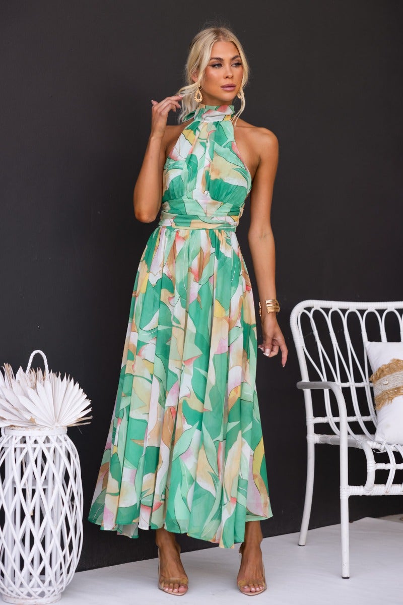 Model wearing a floral print Little Things Maxi Dress in green with a high tie neckline, perfect for summer outings.