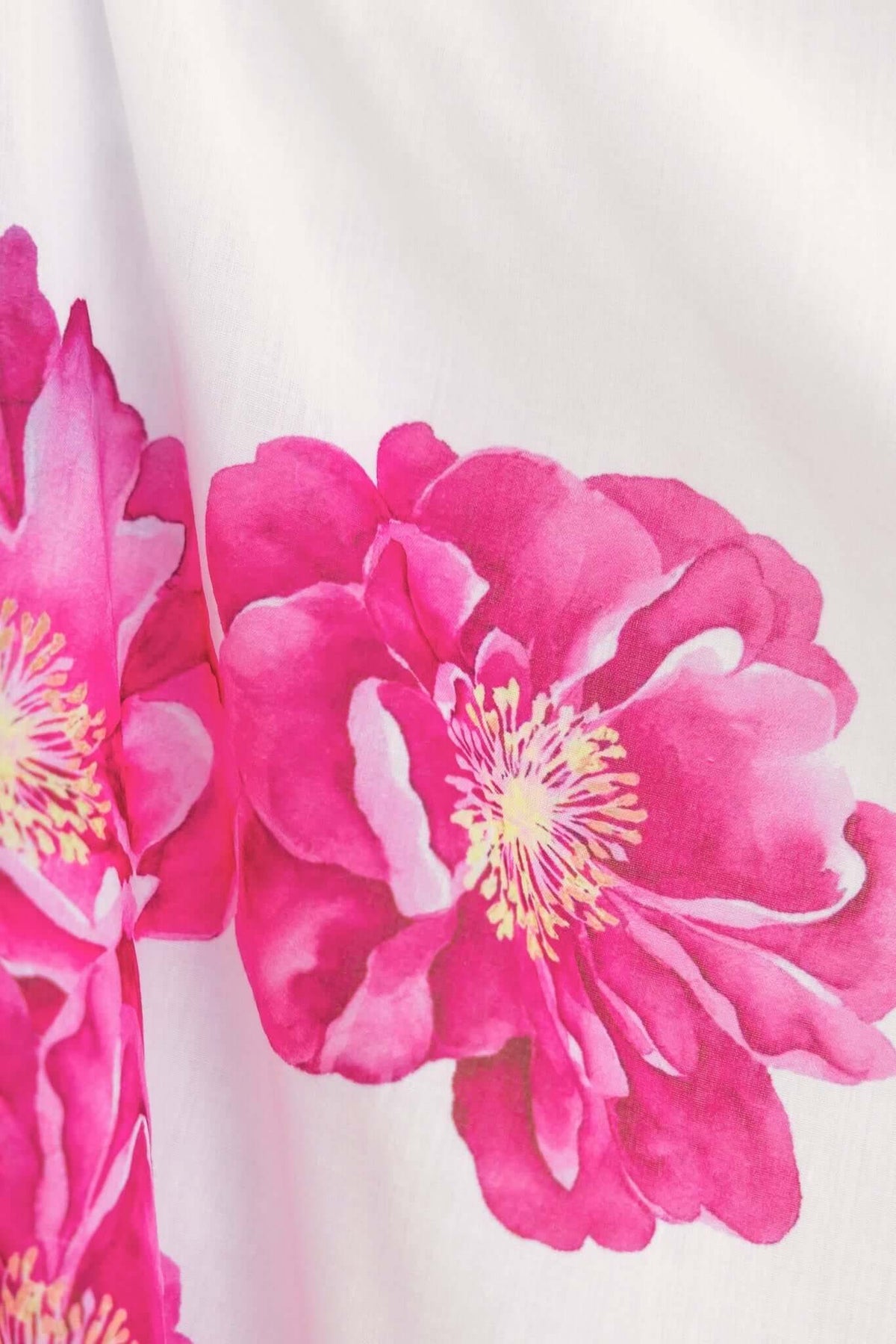 Close-up of vibrant pink peony floral print on a soft white background, showcasing the Pezzi Dress design.