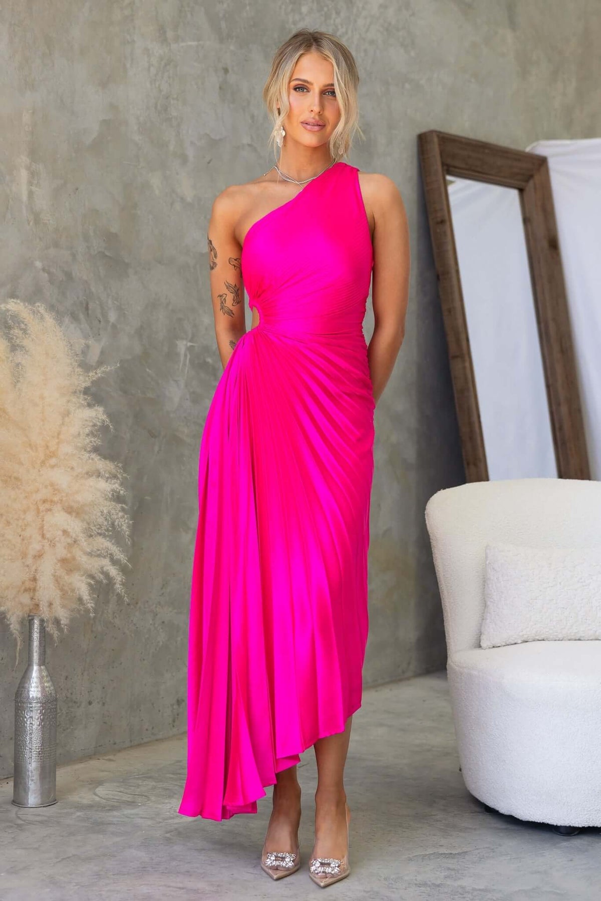 Model wearing vibrant pink Olympia Maxi Dress with one-shoulder neckline and pleated design.