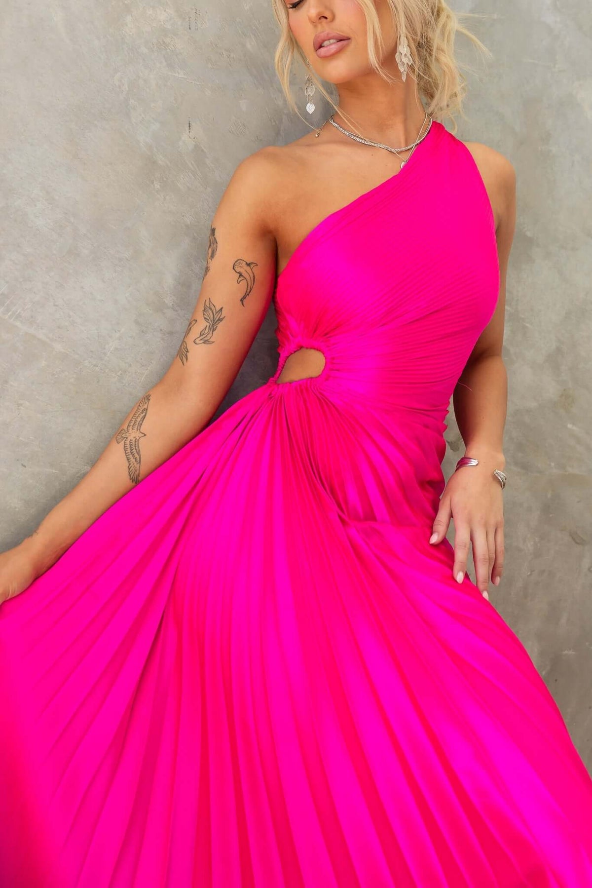 Vibrant pink Olympia maxi dress with one-shoulder neckline and cut-out waist, featuring accordion pleat design.