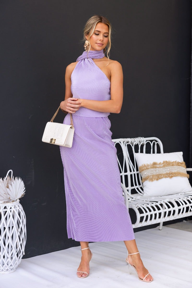 Model wearing Amethyst Maxi Skirt in accordion pleat style, paired with a stylish box bag and heels.