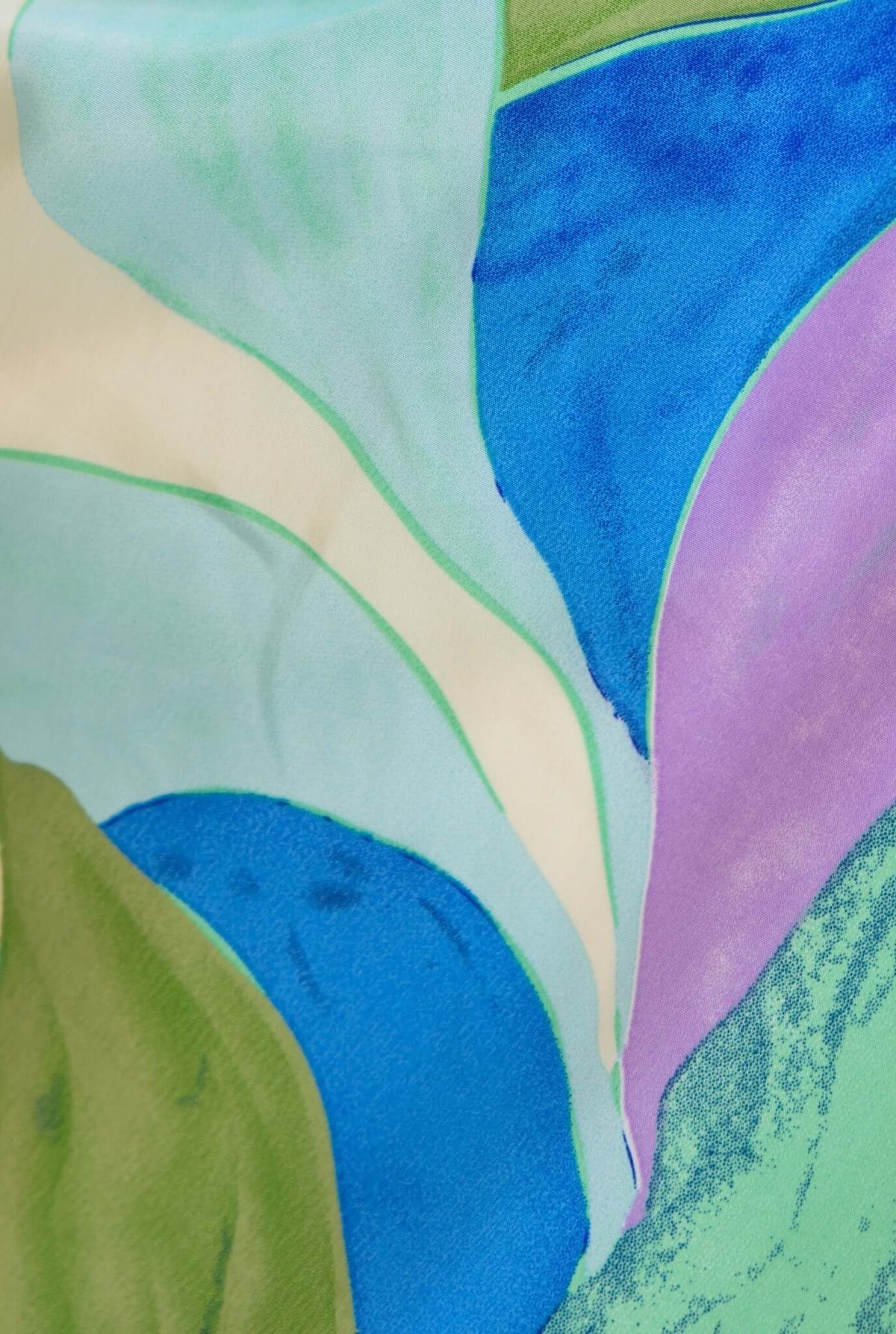 Close-up of colorful fabric featuring abstract swirls in blue, green, and purple tones, perfect for fashion designs.